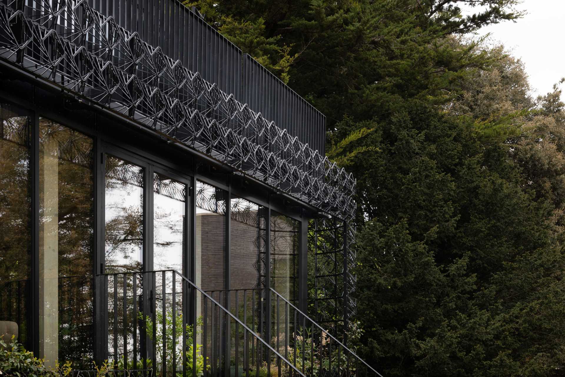 A modern black house with a sculptural facade designed to let plants grow on the exterior over time.