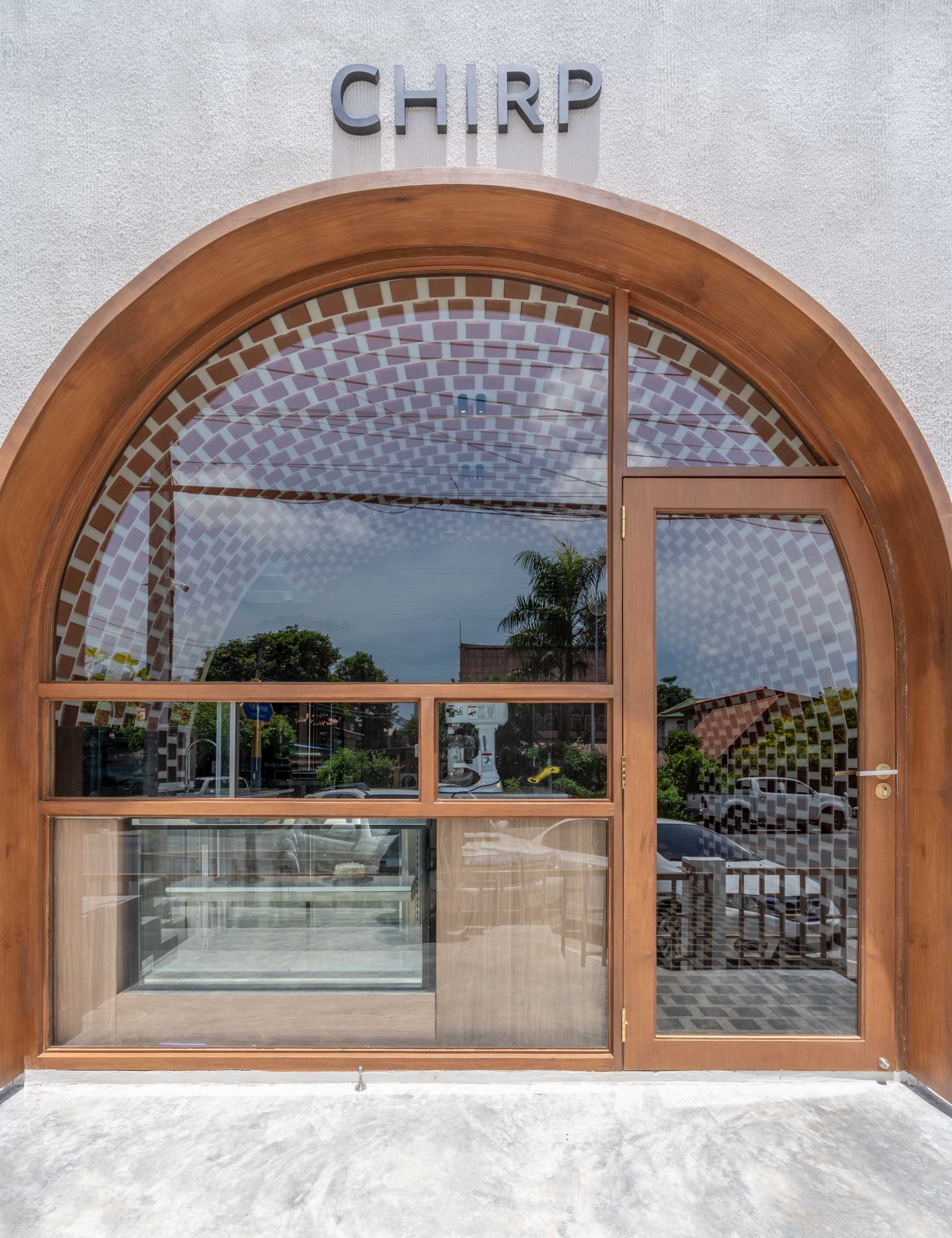 A small cafe with facade that features an arched window detail, and an interior with gradient tiles.