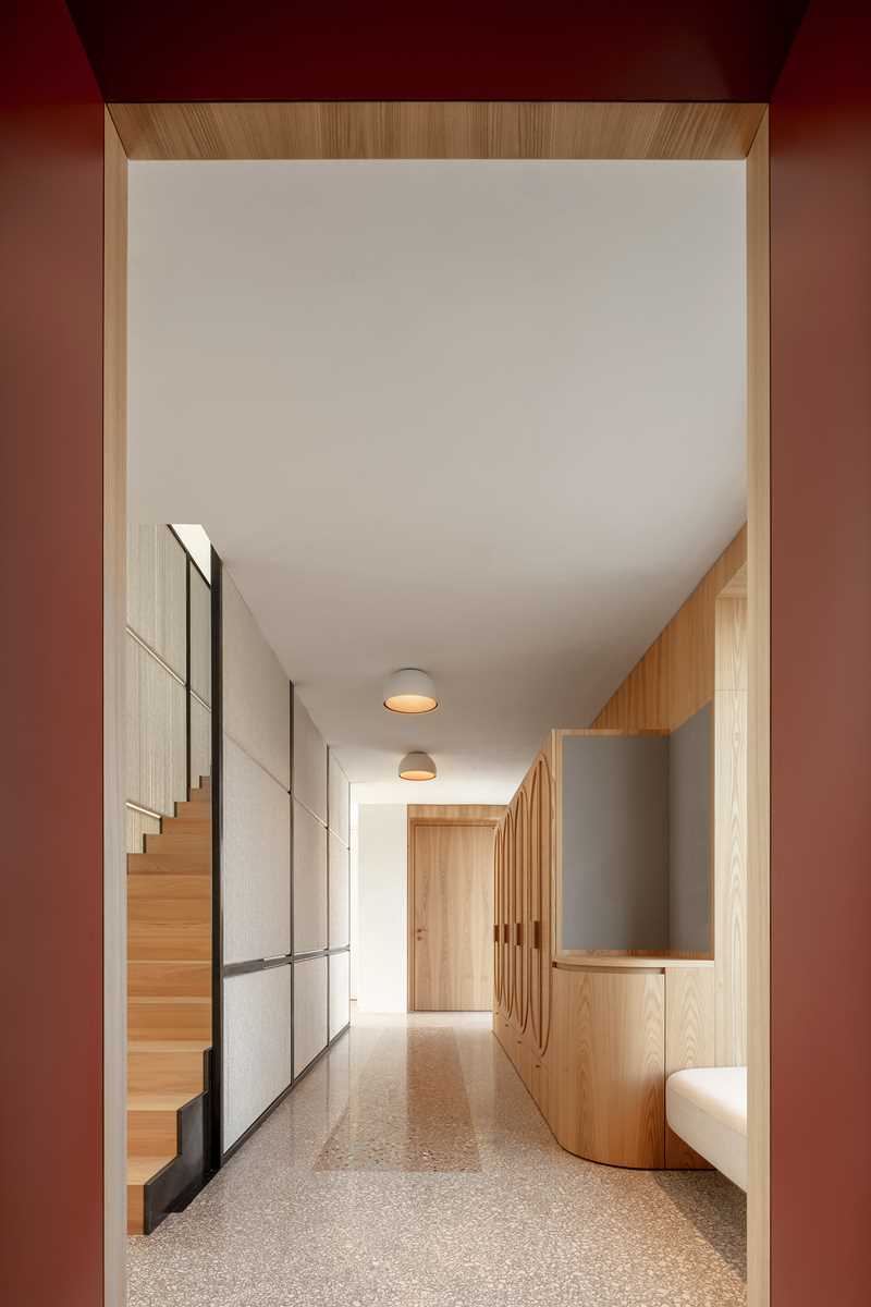 A wall of wood cabinets ends at a built-in bench underneath a window.