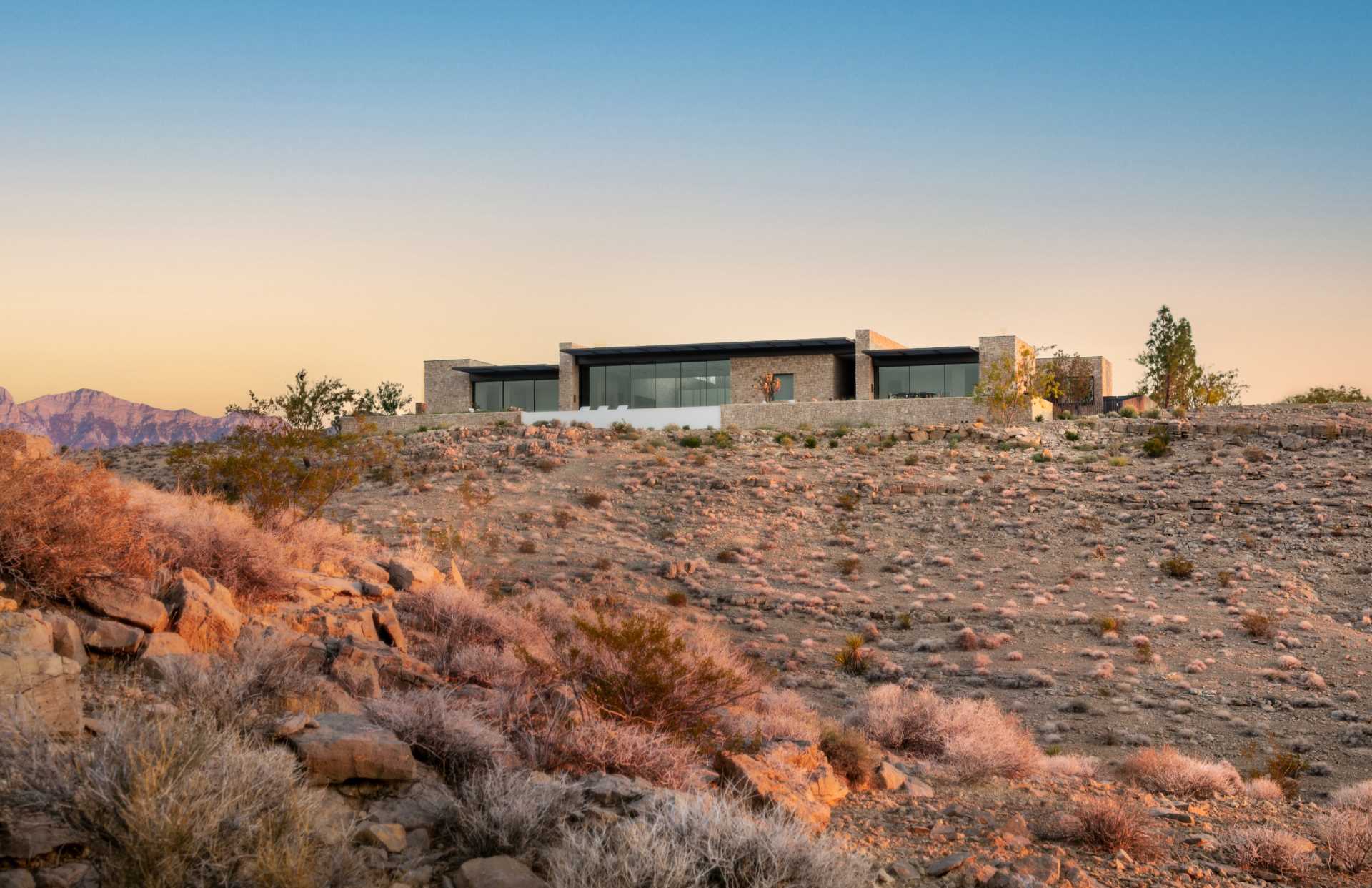 A modern home in the desert features weathered and hot rolled steel, stone walls, sliding glass panel walls, and travertine.