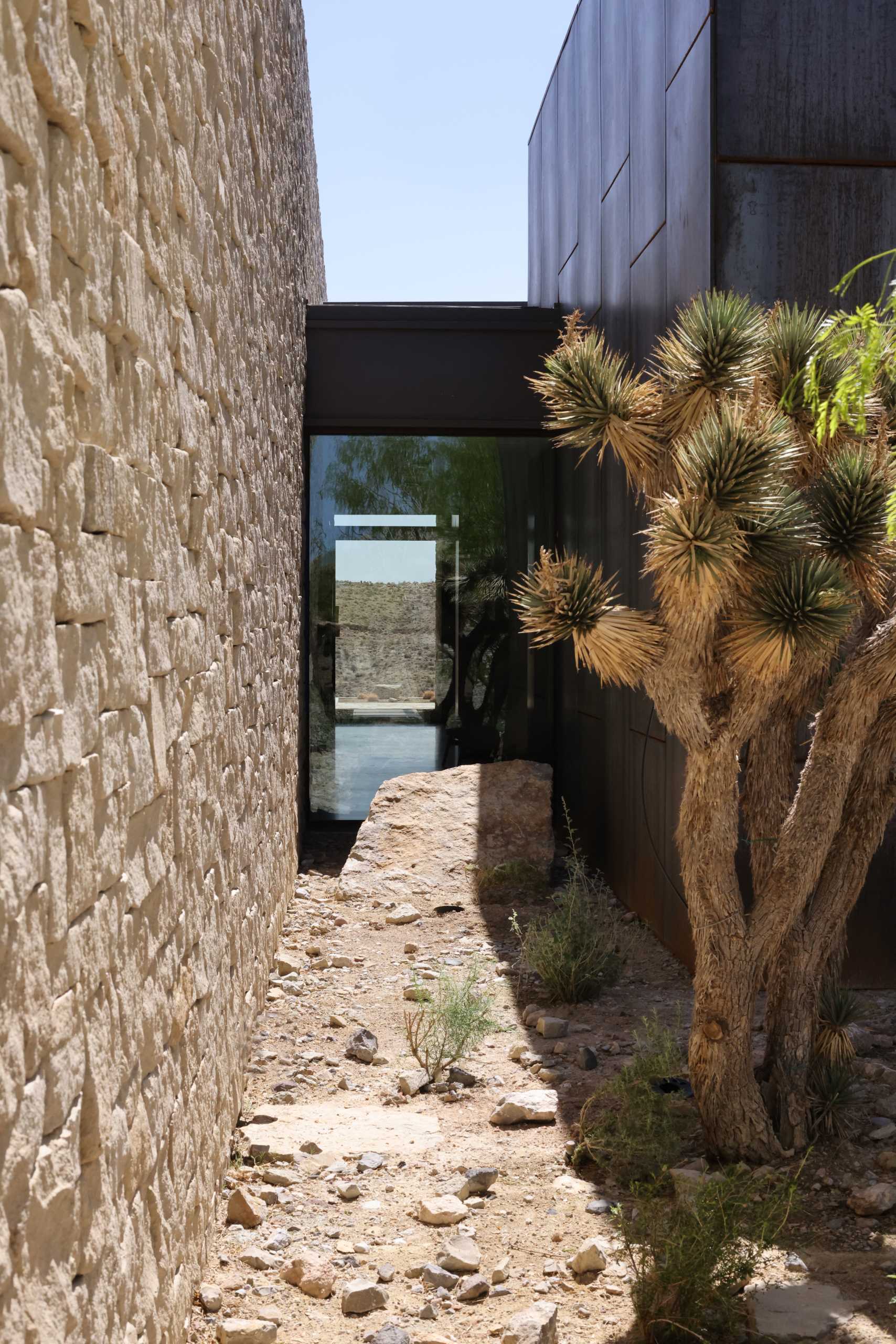 A modern desert home features stone and steel walls.