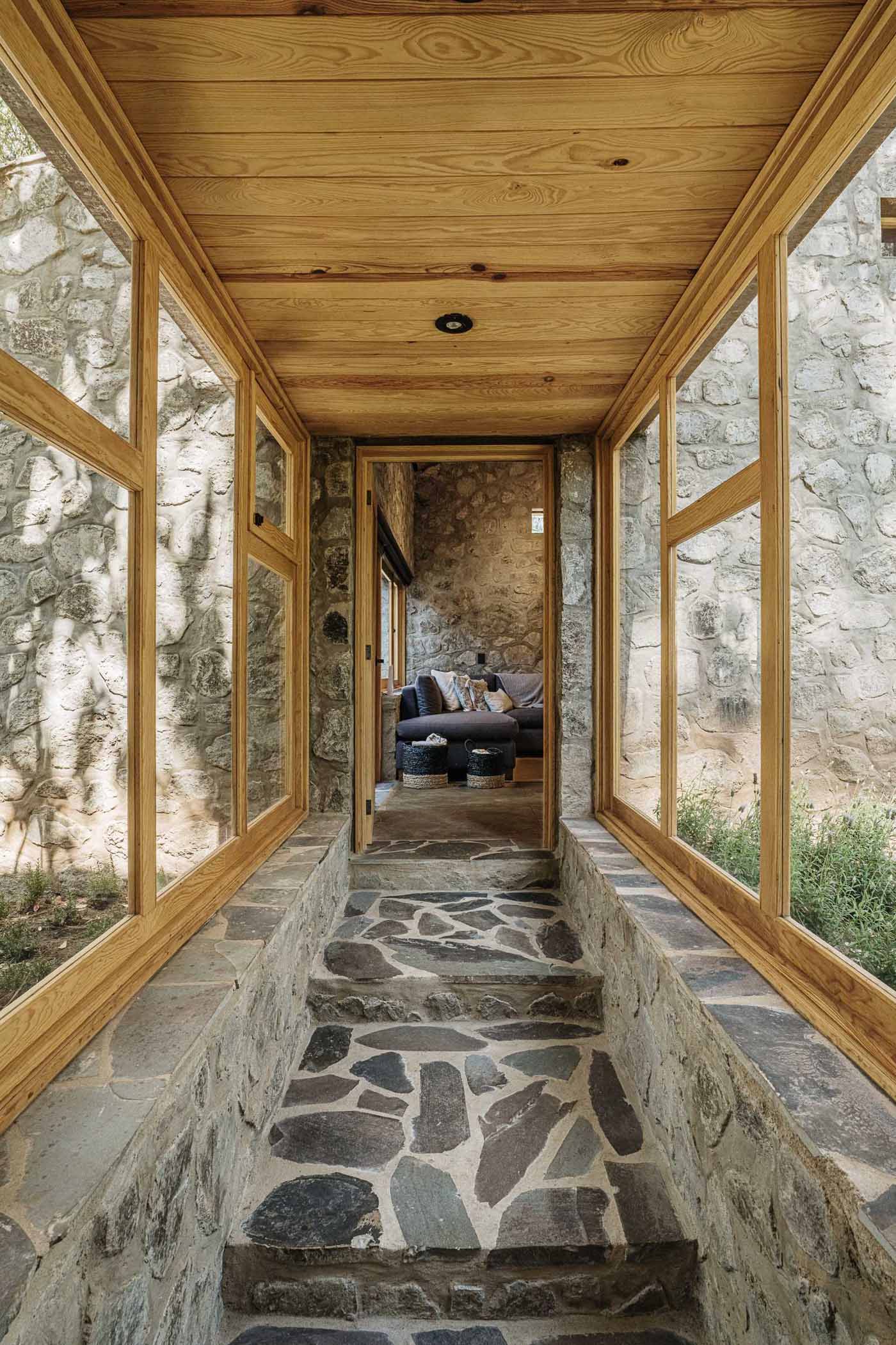 A contemporary home with stone walls, wood framing, and a glass corridor.