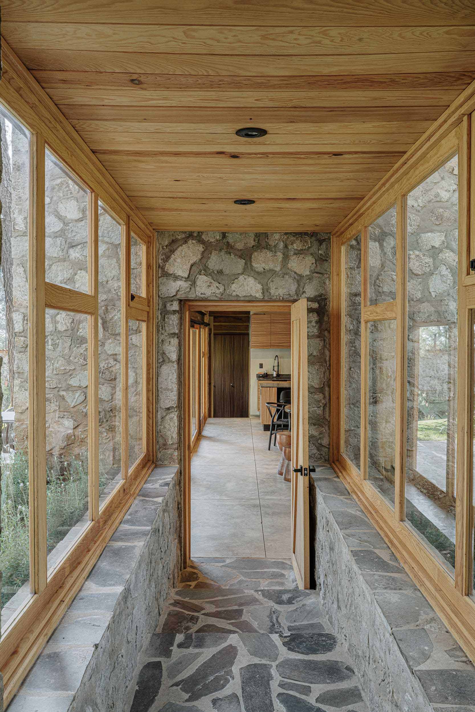 A contemporary home with stone walls, wood framing, and a glass corridor.