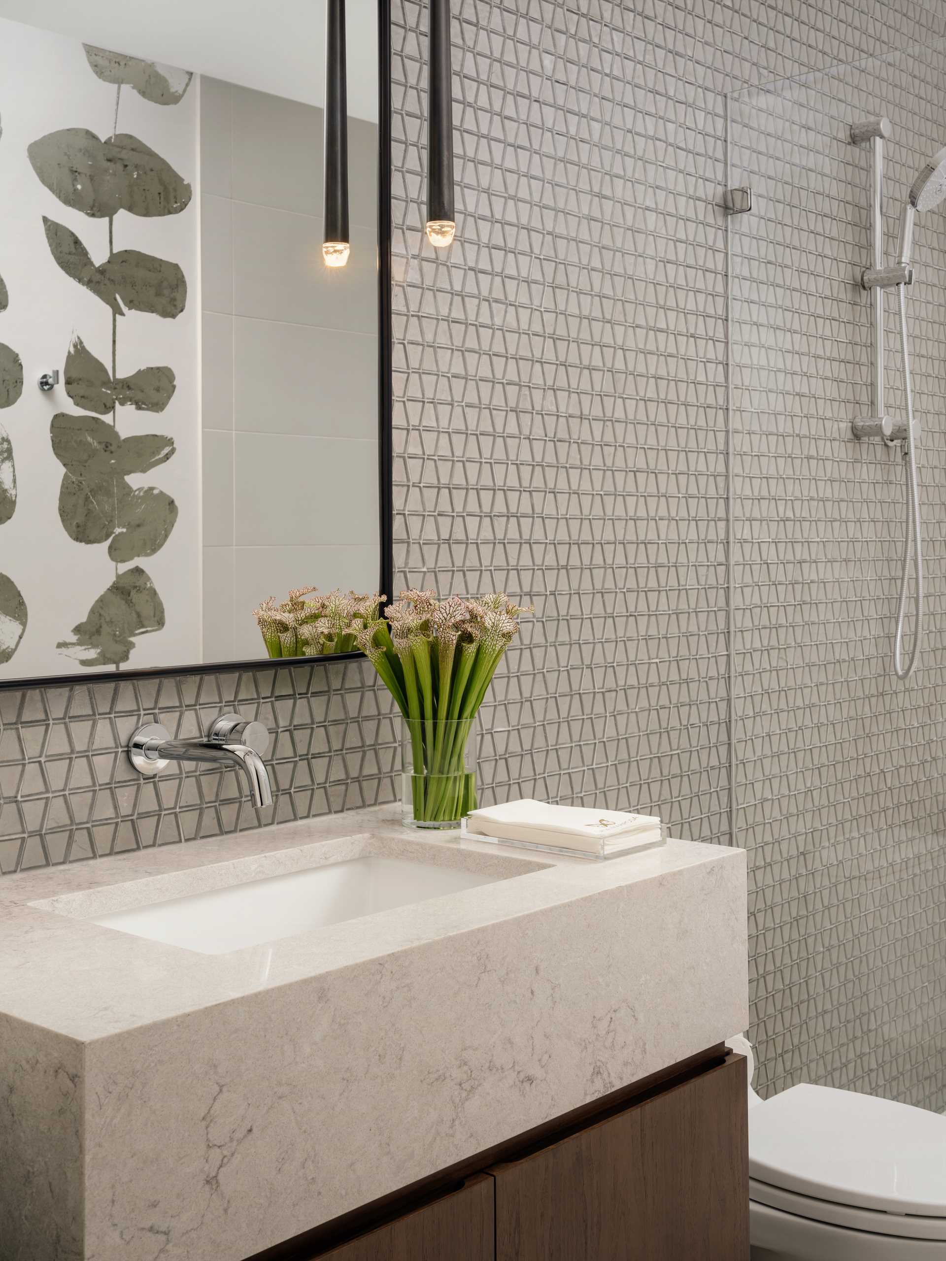 In this modern bathroom, small tiles with a trapezoid shape line the wall.