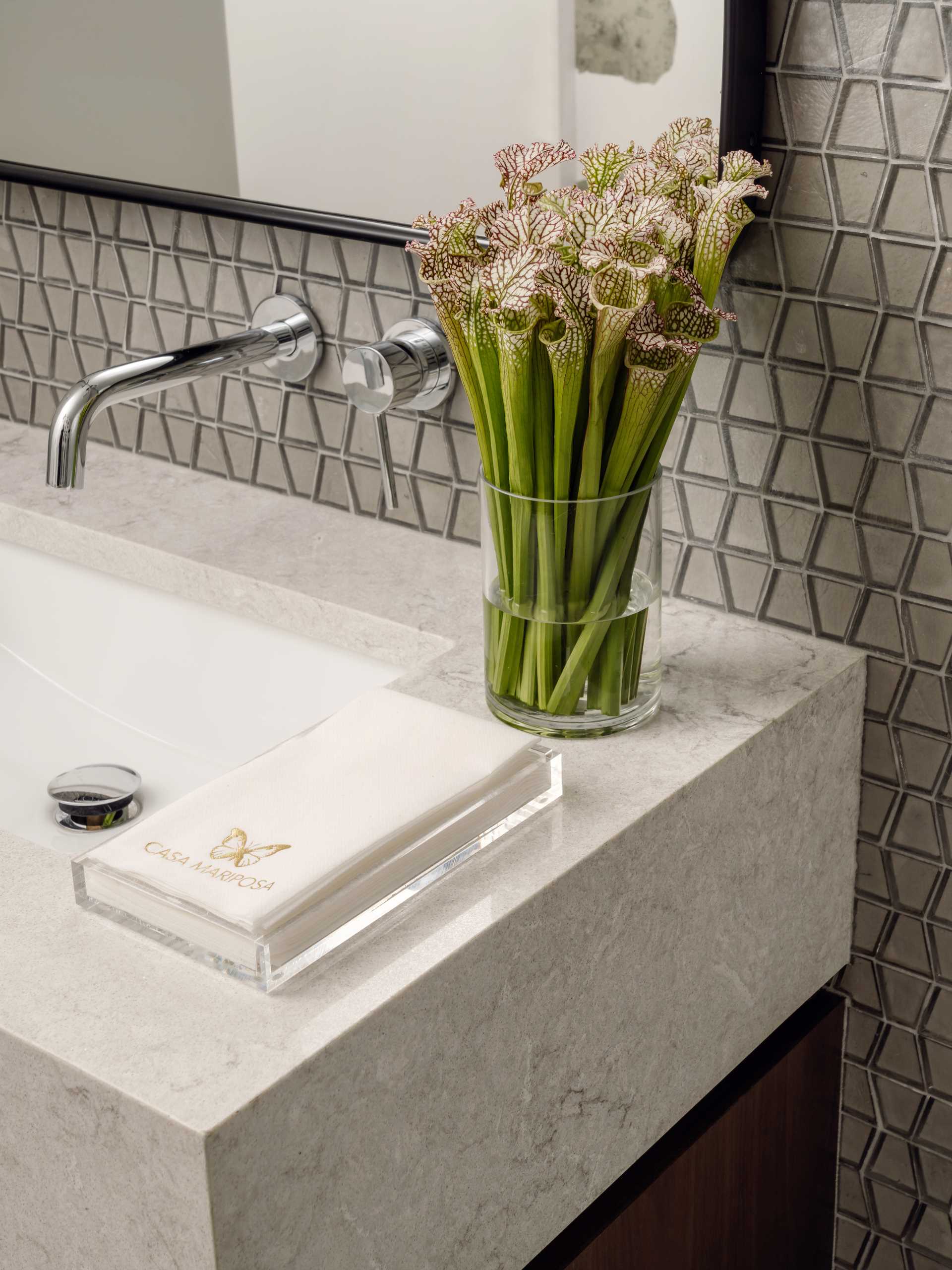 In this modern bathroom, small tiles with a trapezoid shape line the wall.