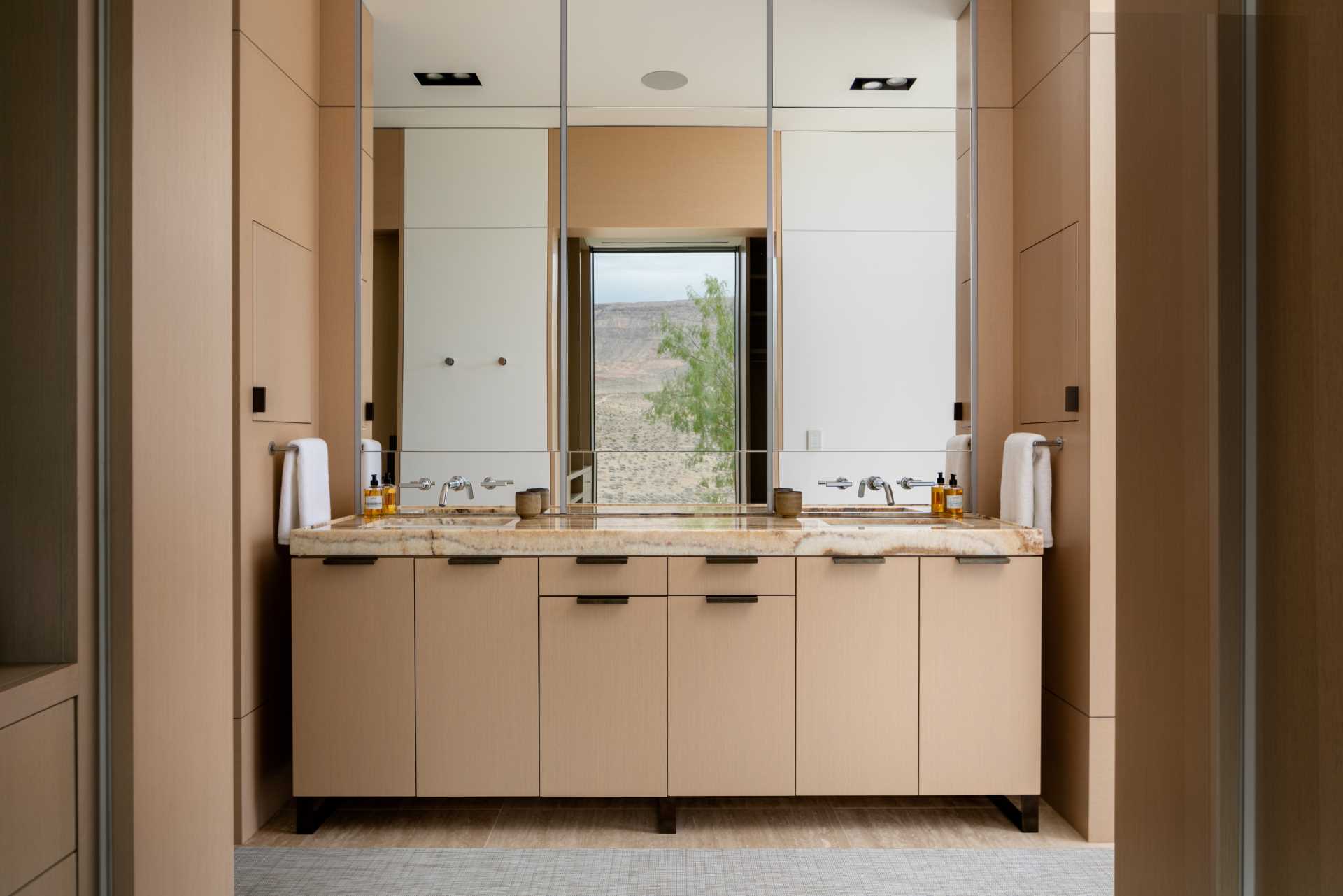 یک حمام مدرن با یک آینه بزرگ که دیوار بالای روشویی را می پوشاند.