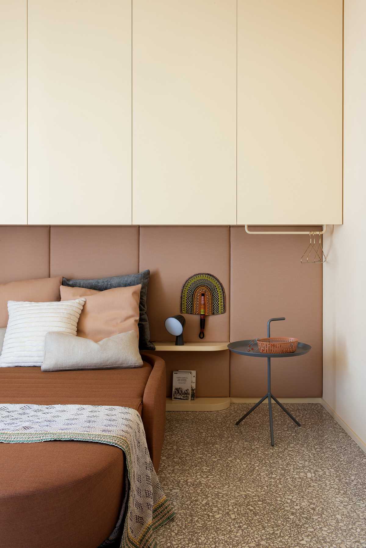 در این اتاق خواب مدرن، یک تخته روکش دار دیوار را می پوشاند، در حالی که کابینت ها بالای تخت قرار دارند.