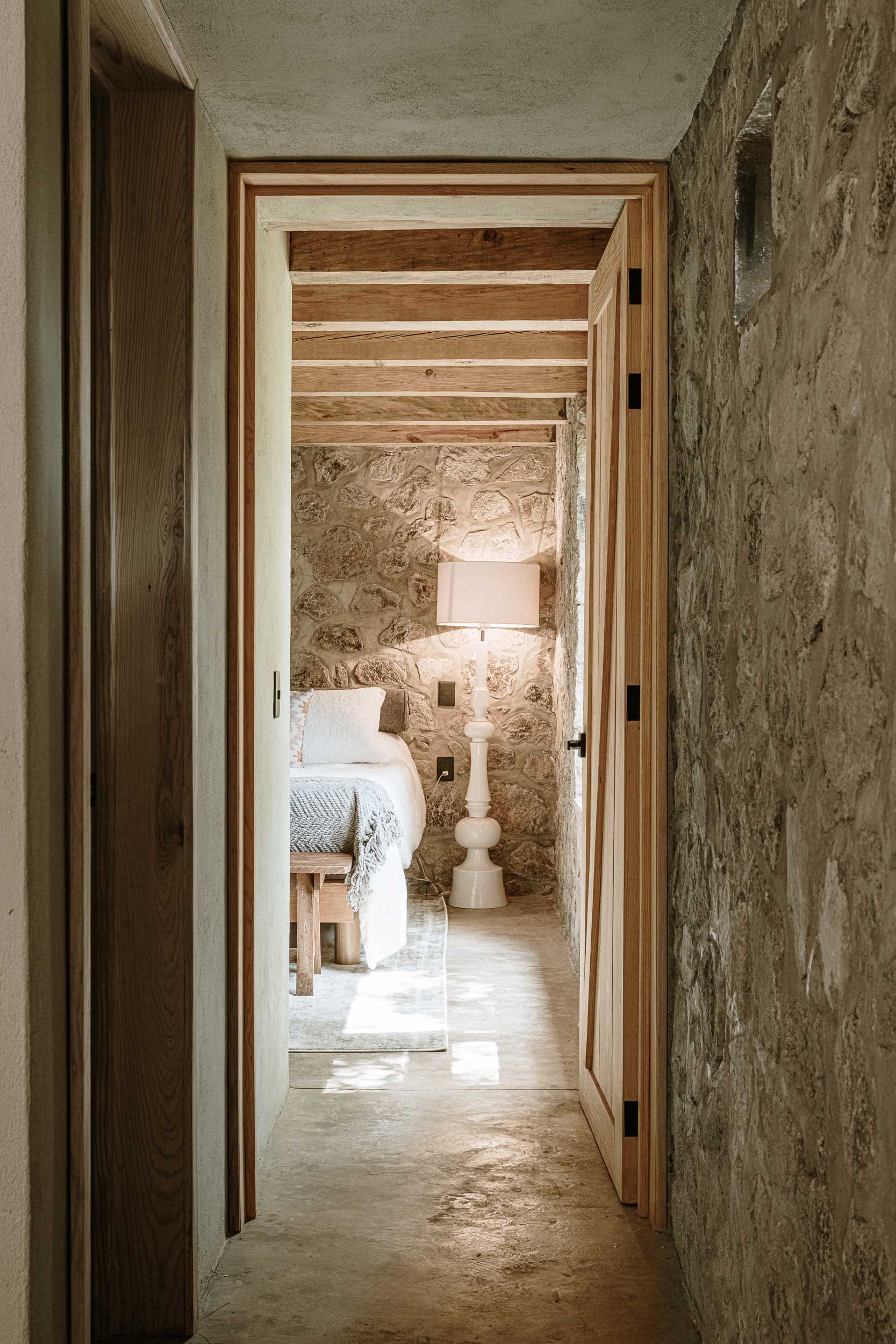 A modern stone and wood bedroom with two beds and built-in cabinetry.