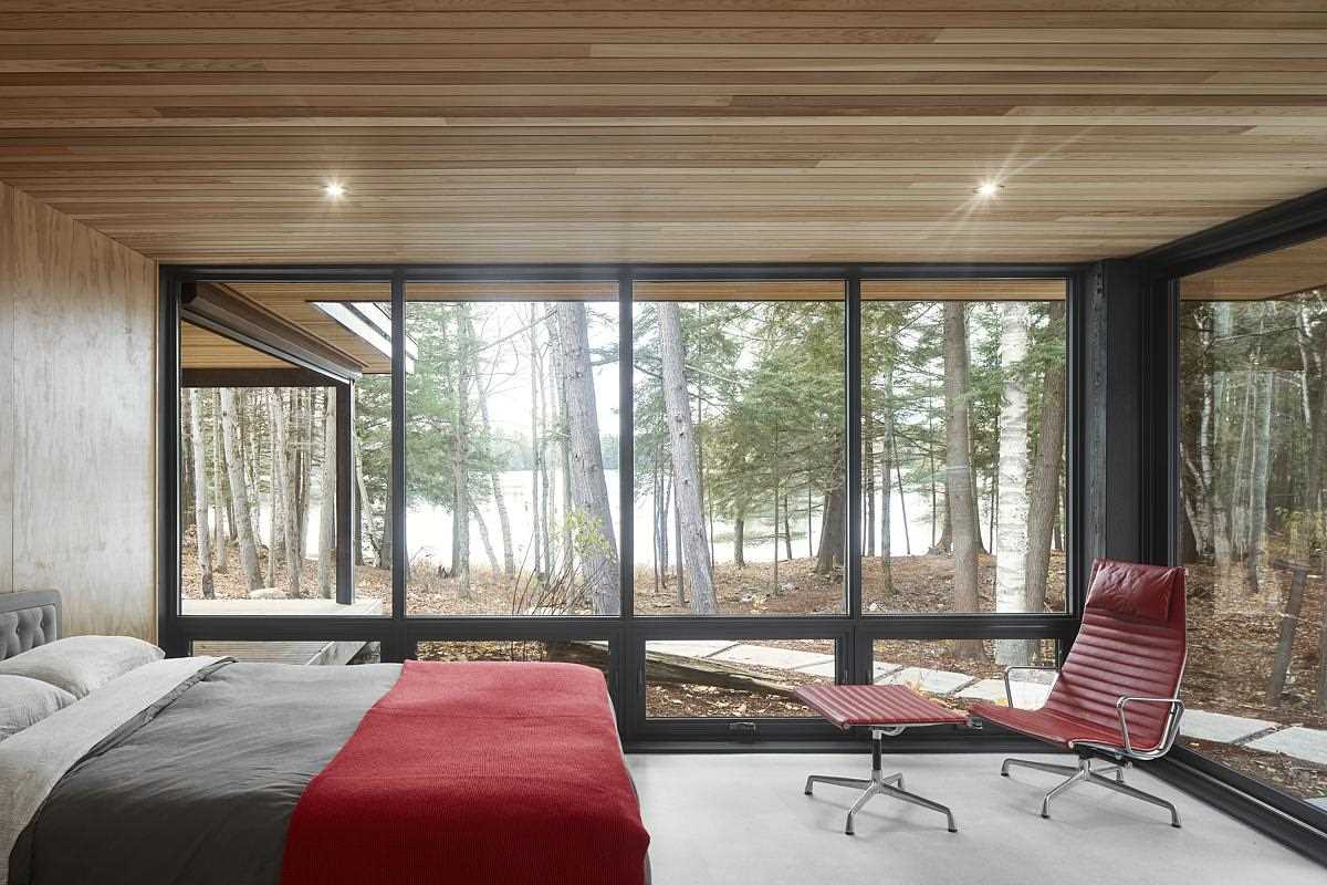 A modern wood-lined bedroom with wood walls and ceiling, and a concrete floor.