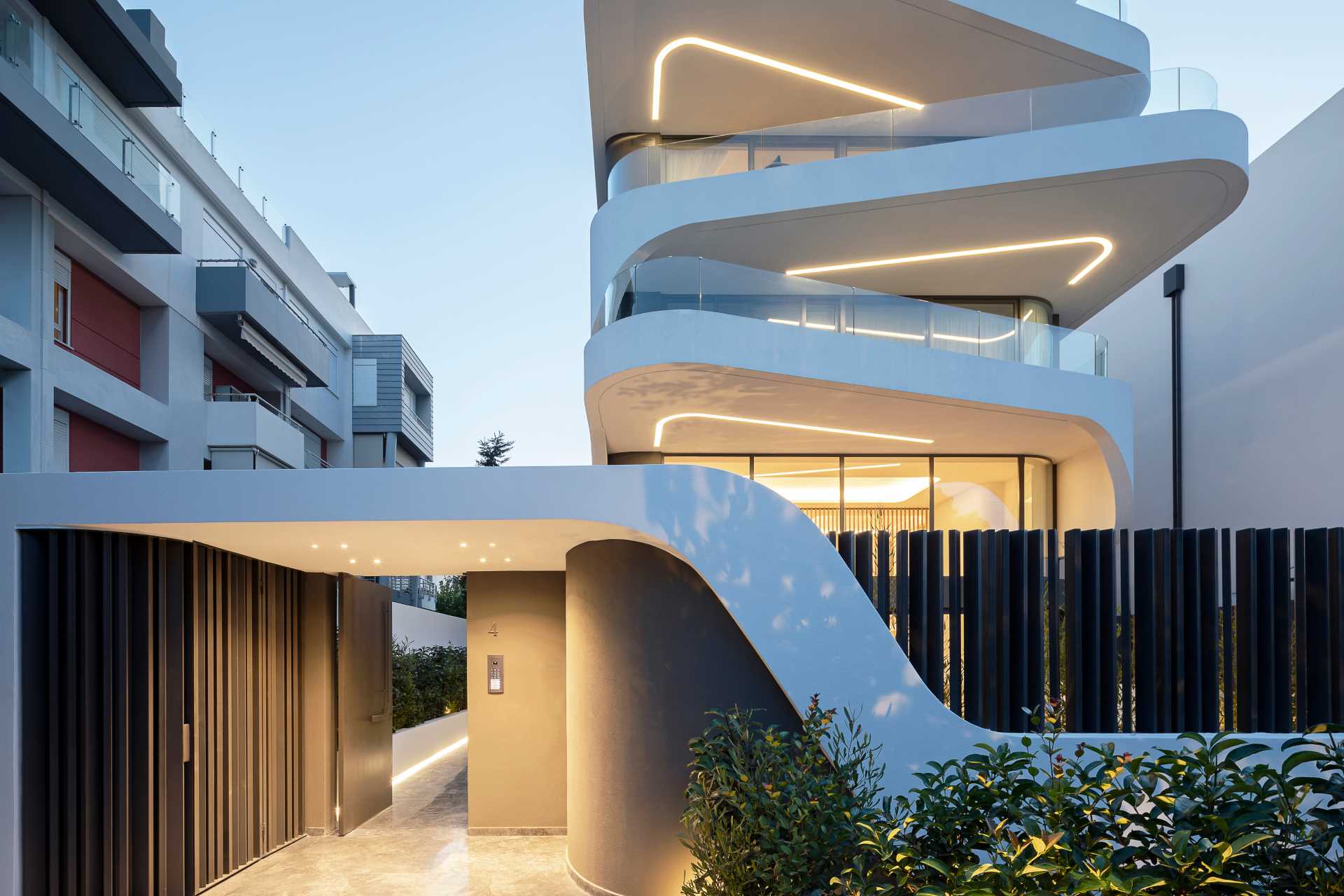 The entry to this modern apartment building is lit well, with a path guiding from the front gate to the main door.