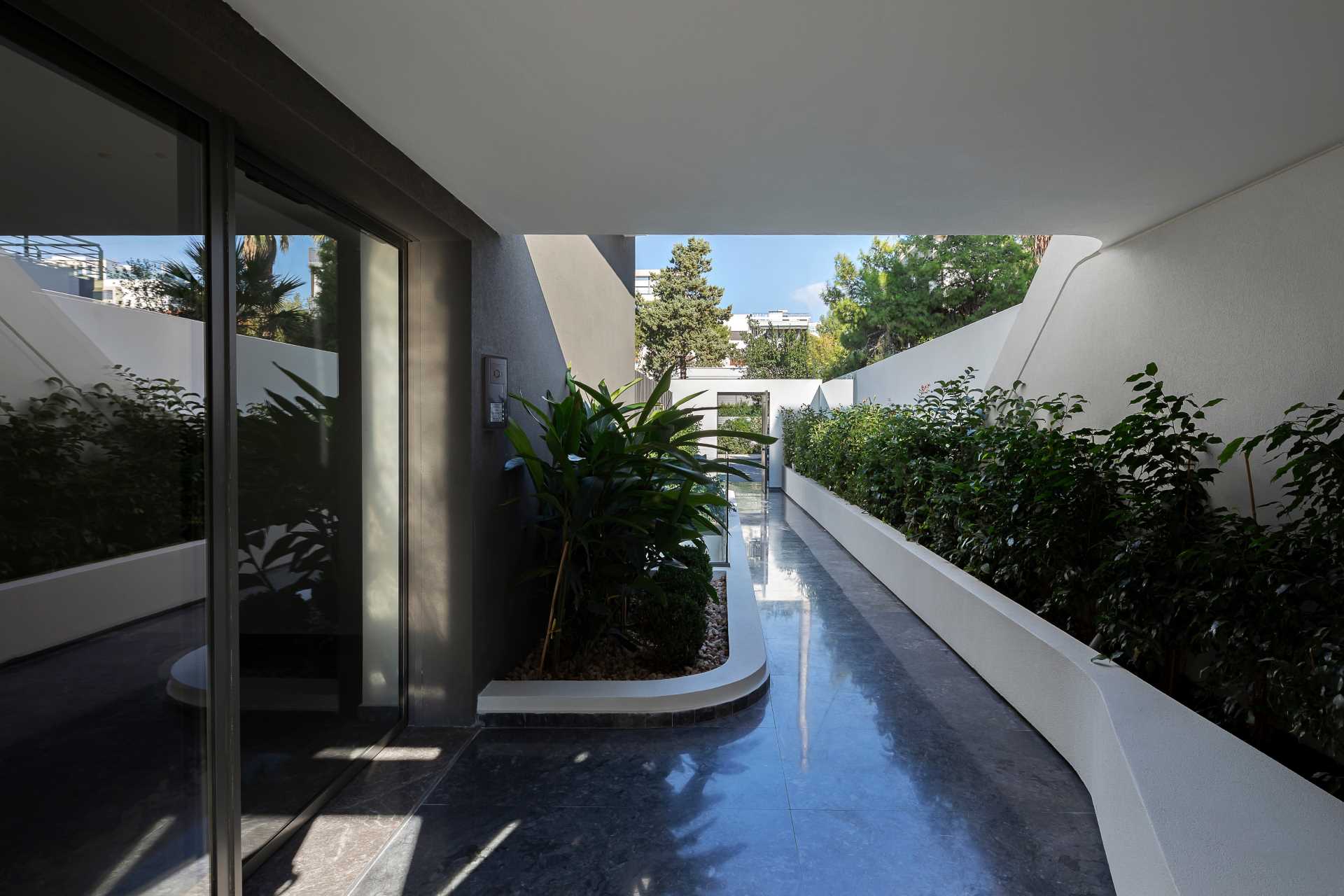 A plant lined entryway to a modern apartment building.