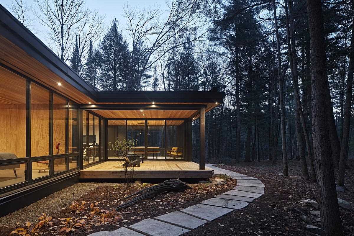 A modern L-shaped cottage with black exterior and large roof overhangs.