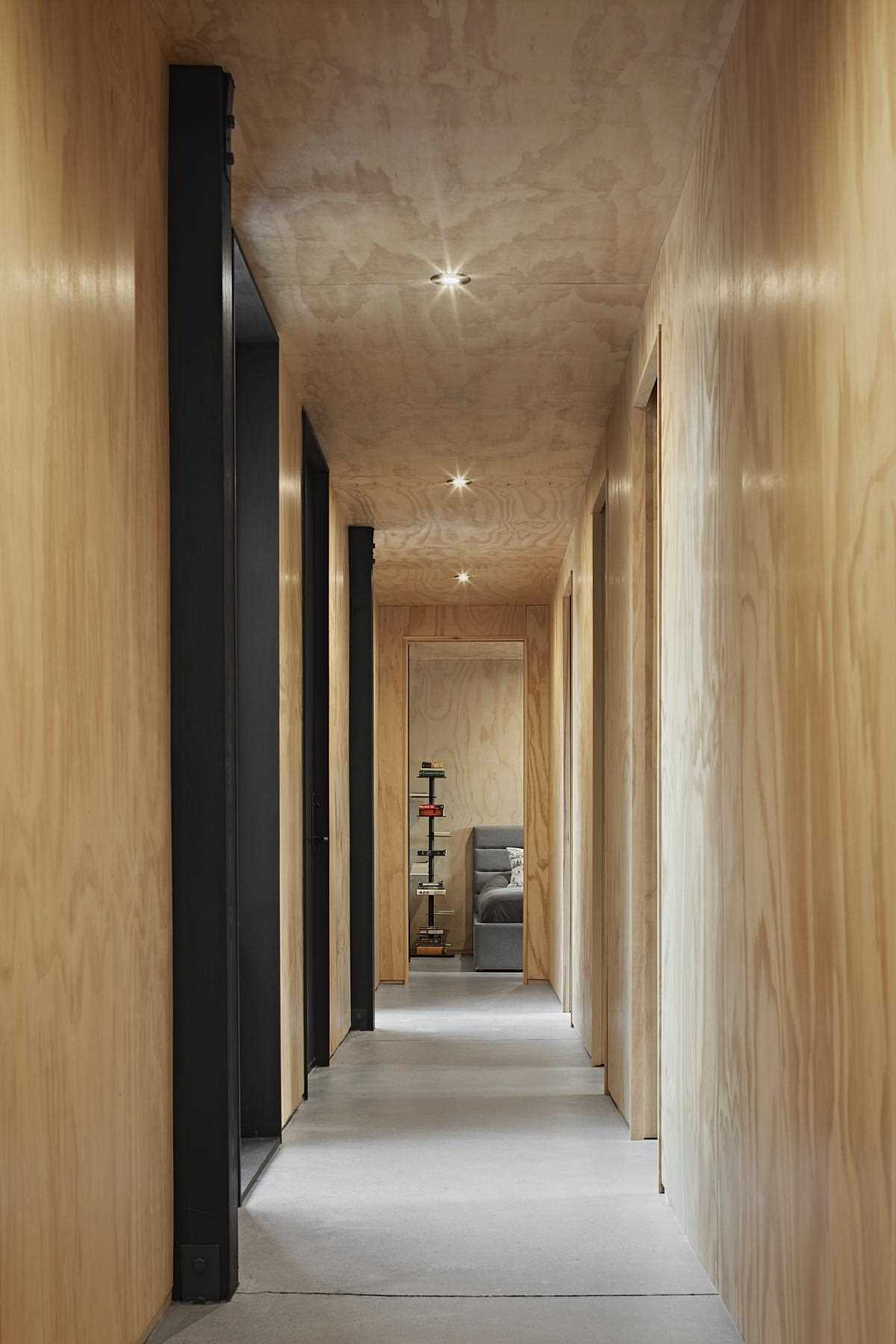 A modern wood-lined hallway with concrete floor and black accents.