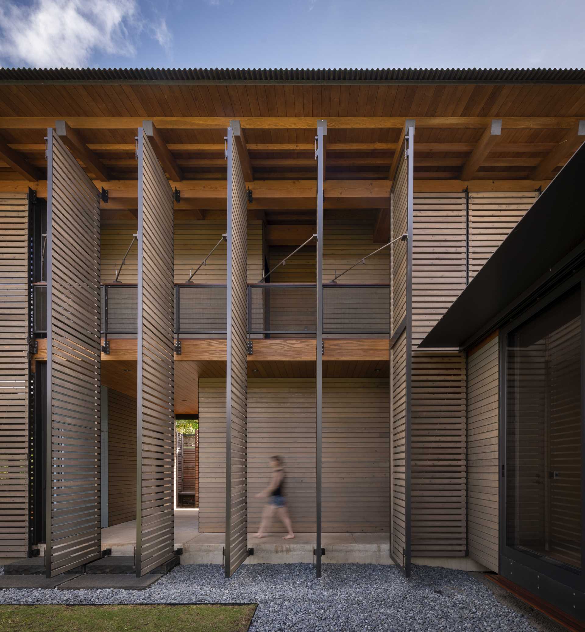 A modern home in Hawaii includes a series of operable shutter screens that wrap most of the building facade.