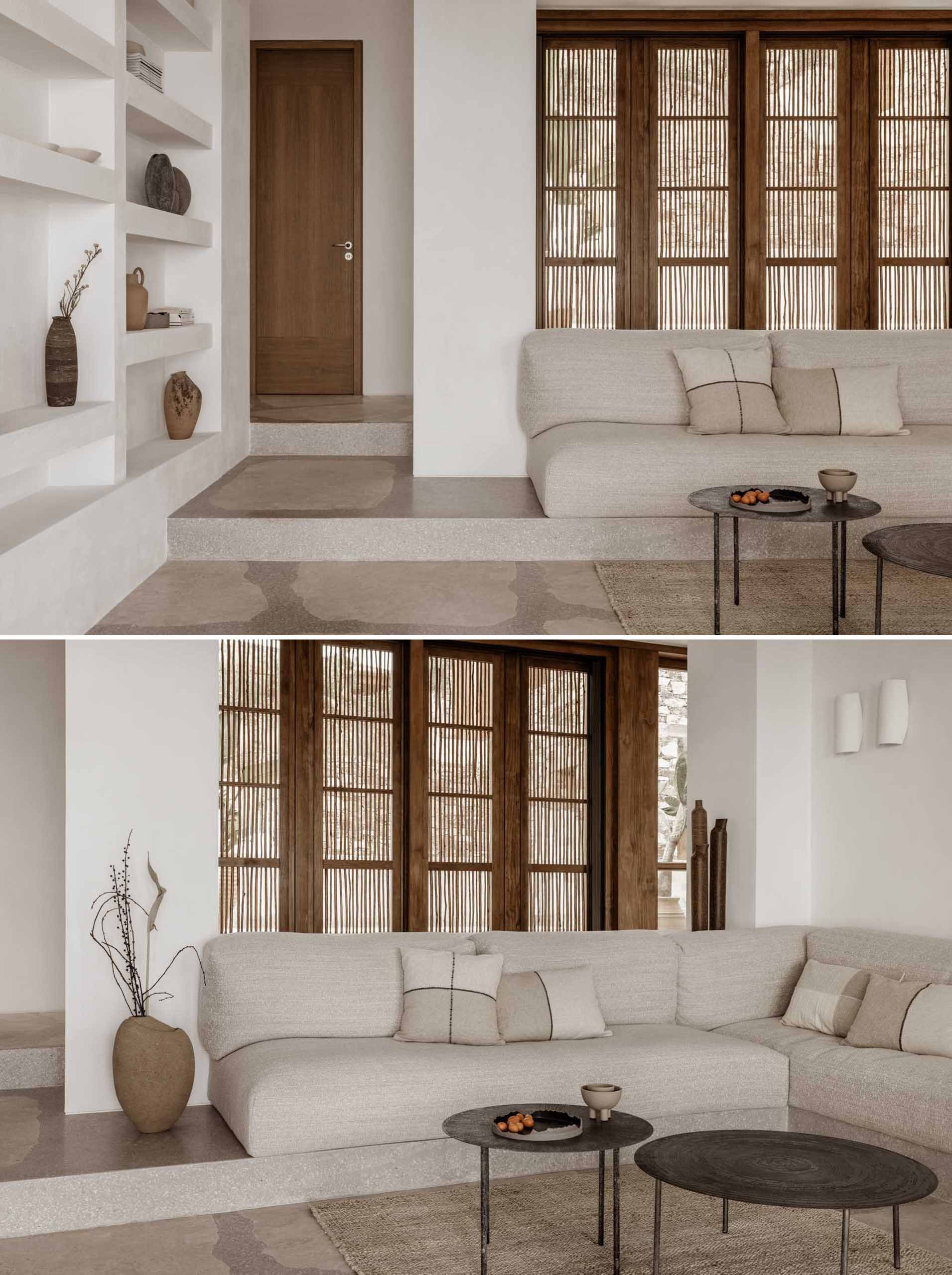 A modern living room with a neutral color and material palette, and built-in shelving and doors that open to a terrace.