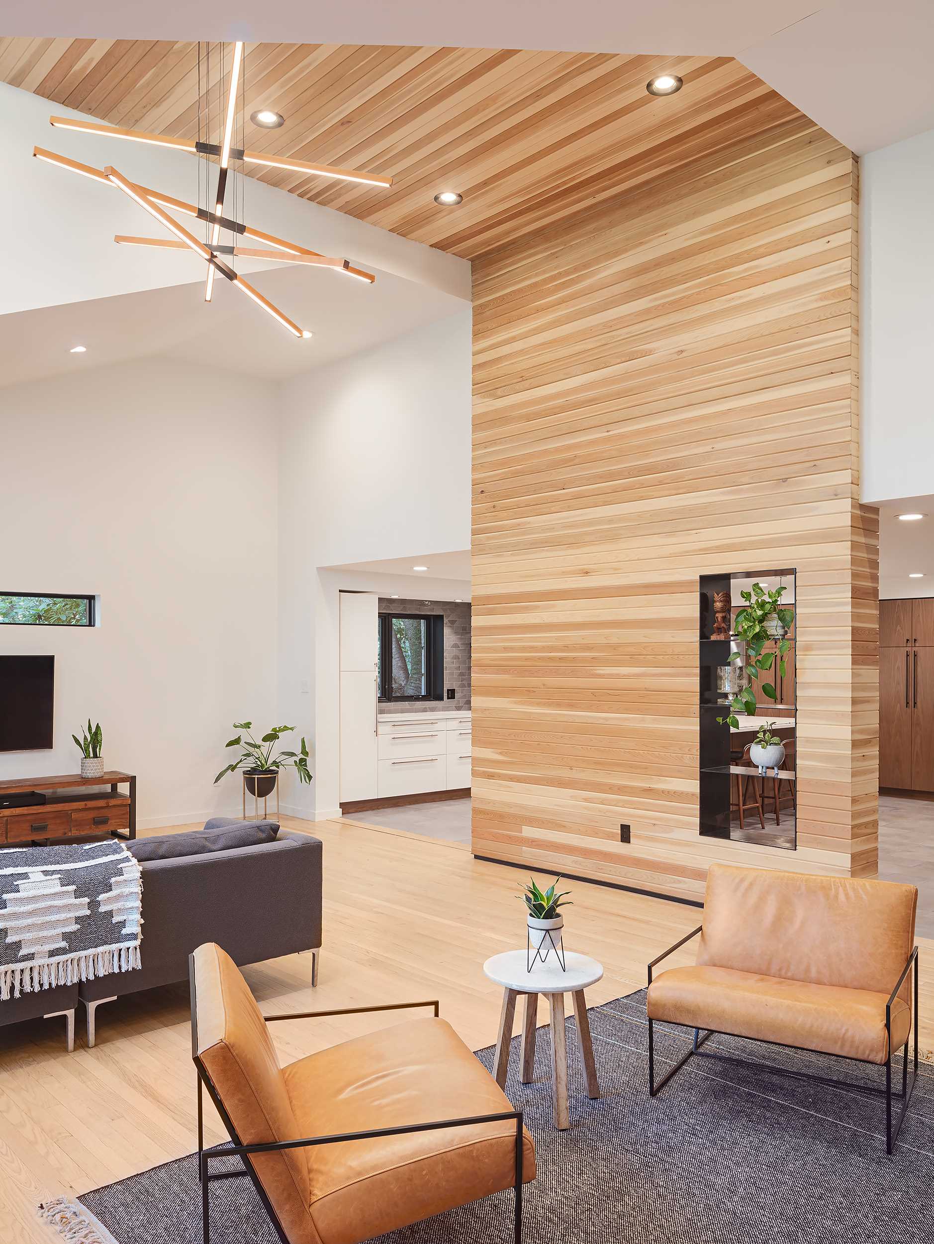 A cedar-clad accent in this living room wraps from the wall to the ceiling and includes steel-lined pass-through shelving.