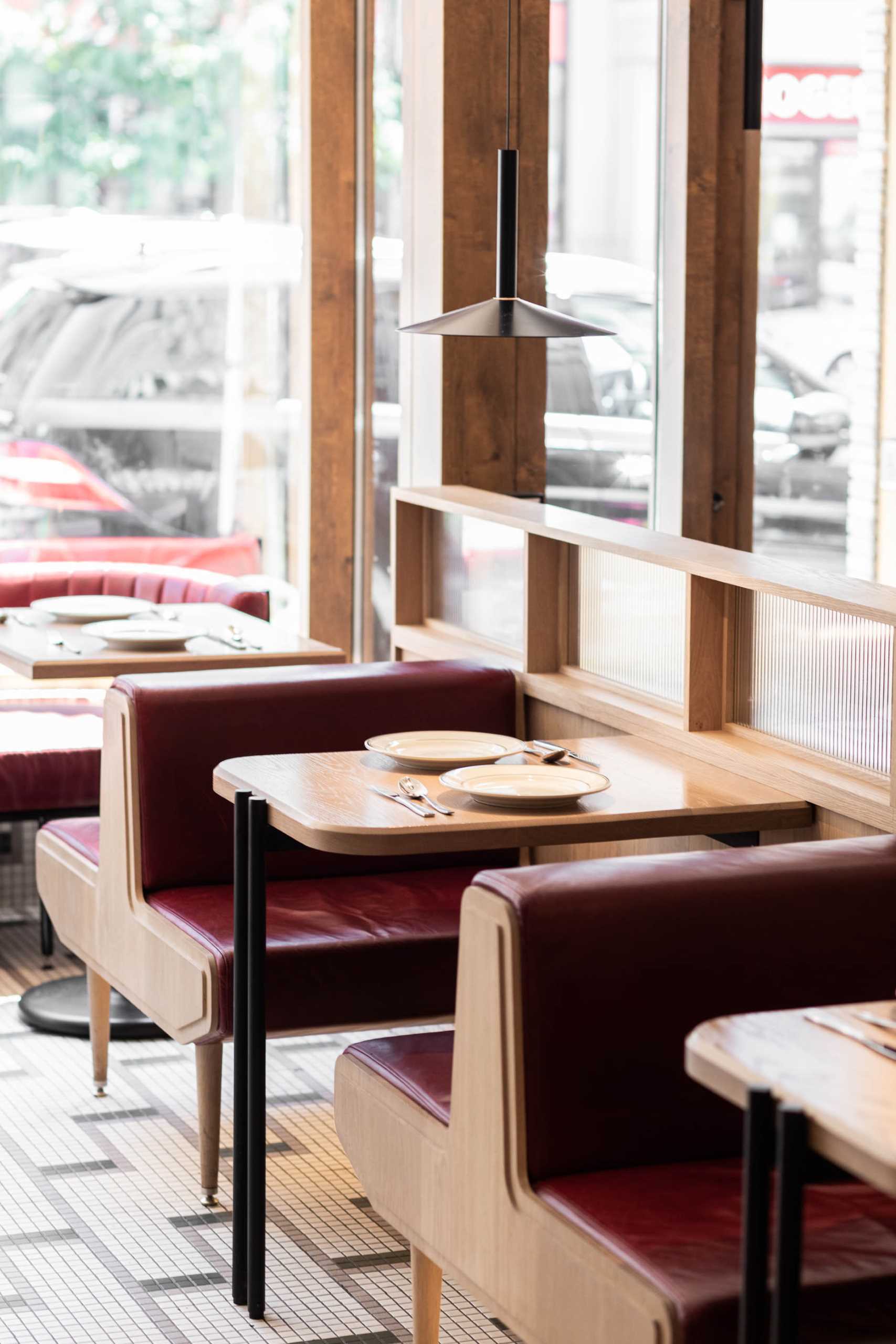 A modern pizzeria that features tile floor, banquette seating, a farm table, and a wall of shelving.