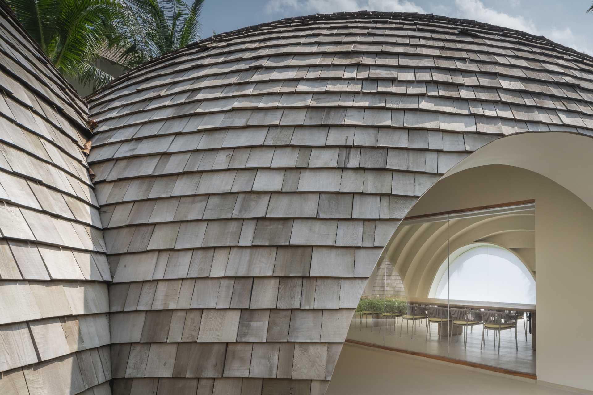 A modern hotel lobby whose design is inspired by the shape and interior of a coconut, and features a shingle-clad exterior.