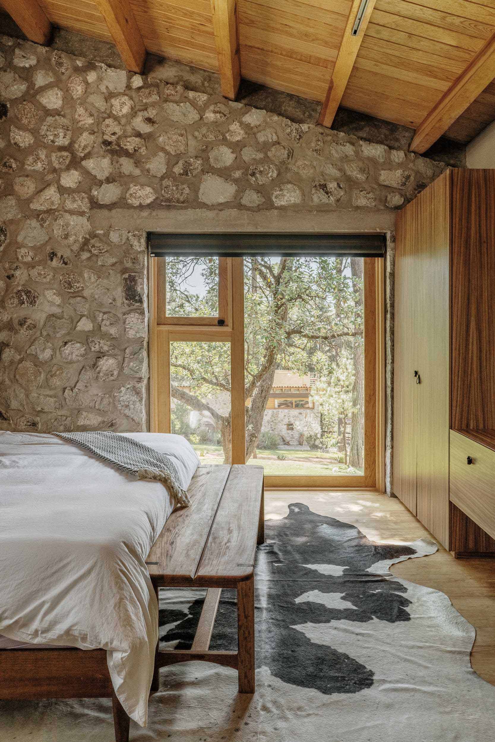 یک اتاق خواب مدرن از سنگ و چوب با منظره بالای درخت.