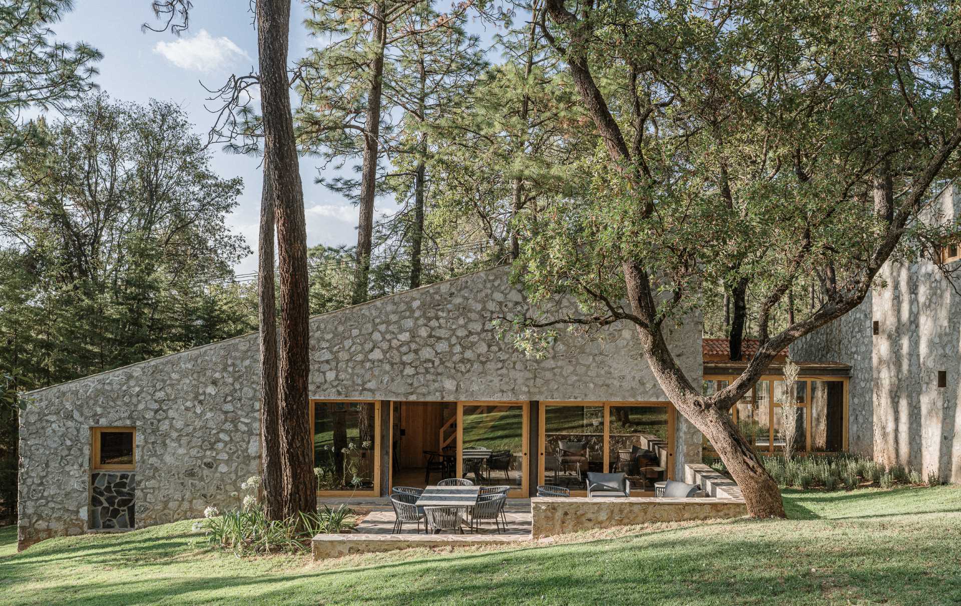 A contemporary stone, wood, and glass home with an outdoor patio.