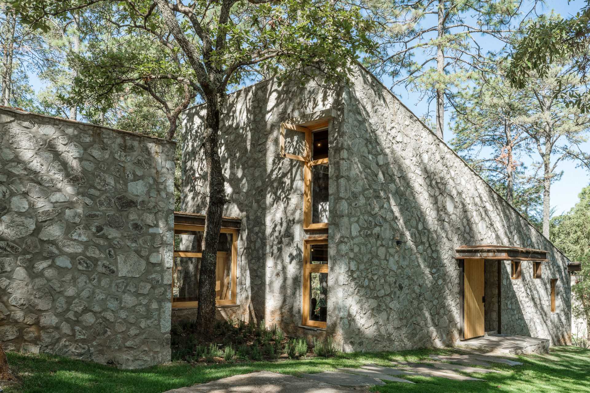 A contemporary stone, wood, and glass home with an outdoor patio.