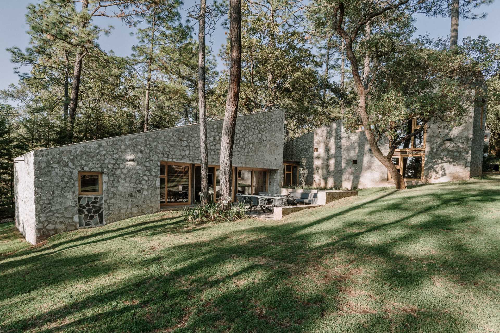 A contemporary stone, wood, and glass home with an outdoor patio.