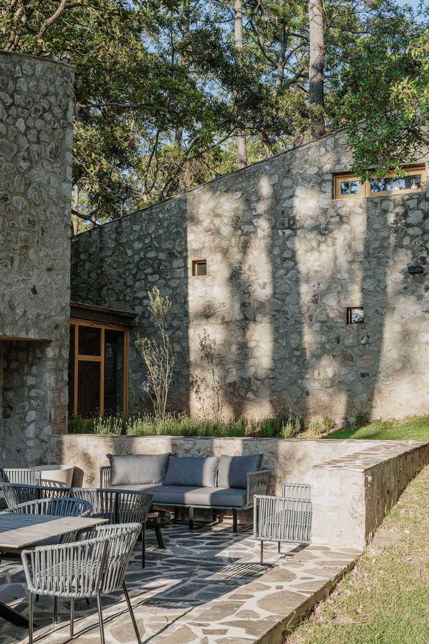 A contemporary stone, wood, and glass home with an outdoor patio.