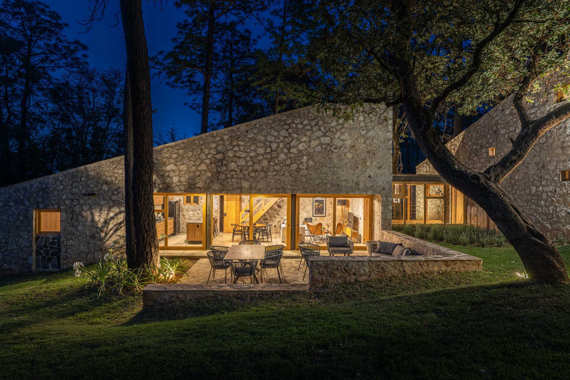 A contemporary stone, wood, and glass home with an outdoor patio.
