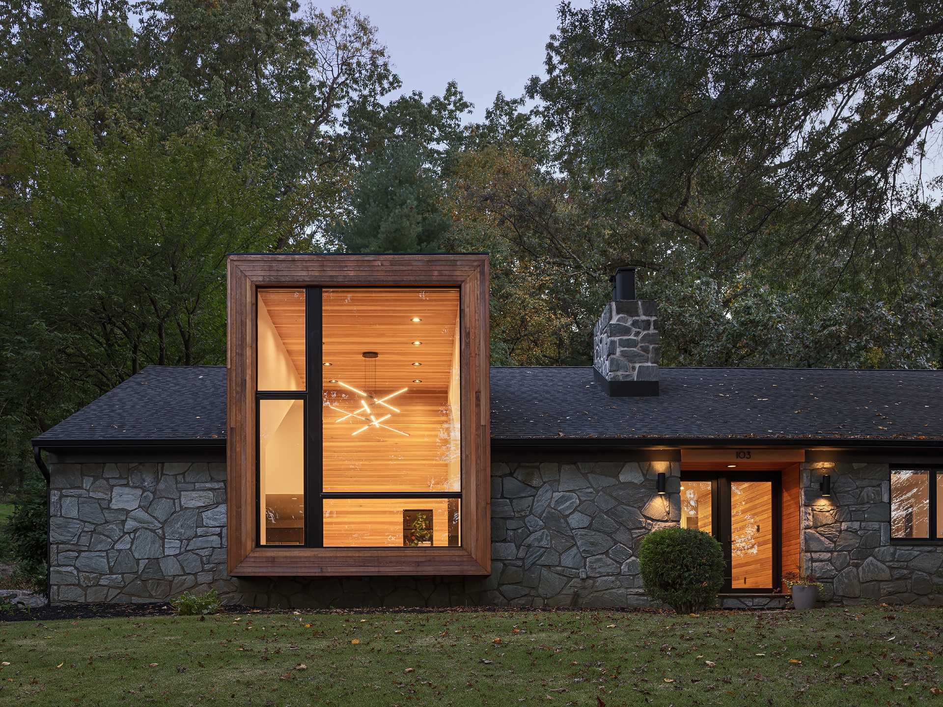 The cedar cladding from the exterior of this 1950s ranch home continues through to the interior ceiling and wall between the living room and the kitchen/dining area.