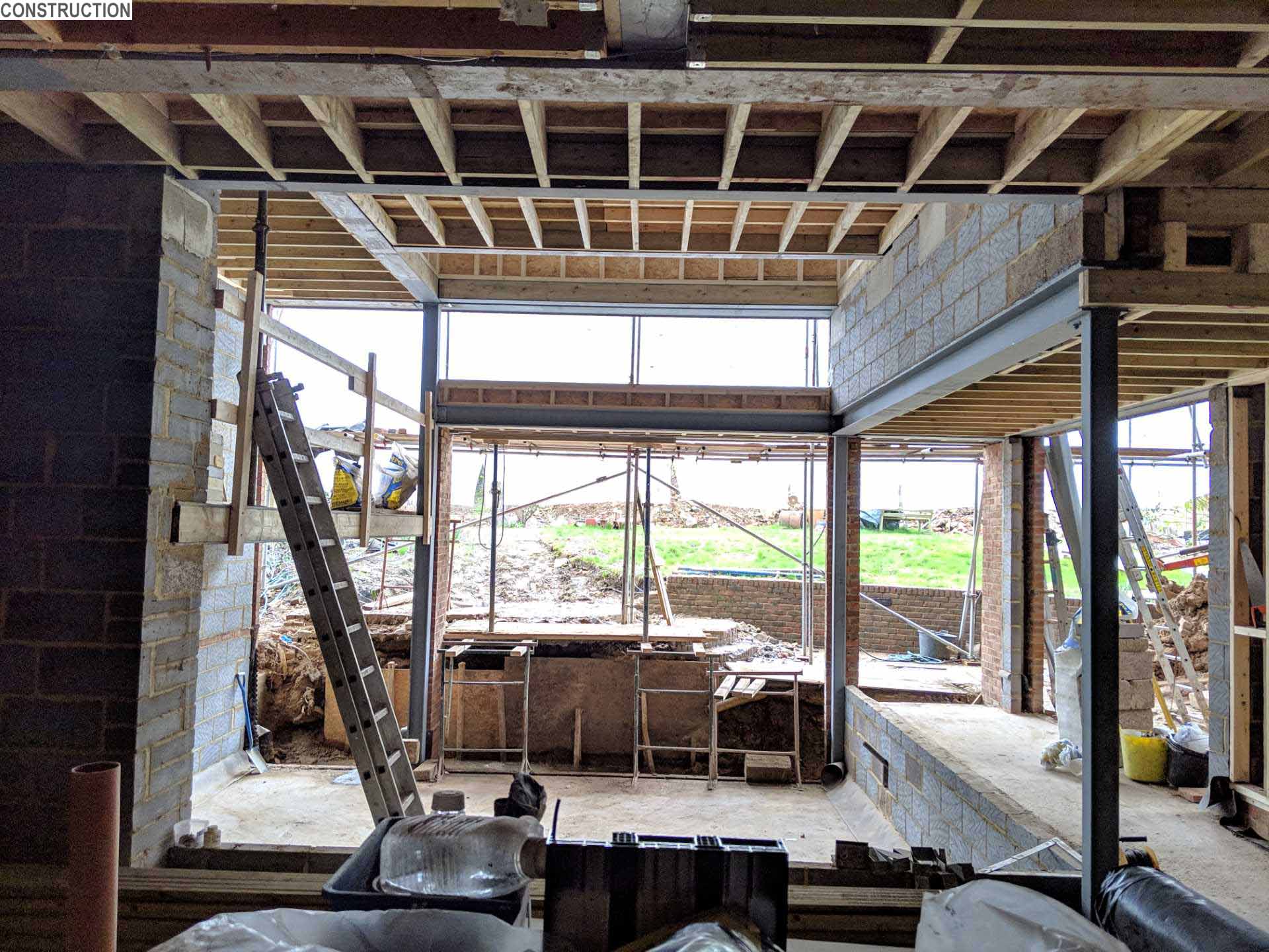 Construction photo - A 1920s British home received a modern rear addition with a sunken living room and mezzanine reading level.