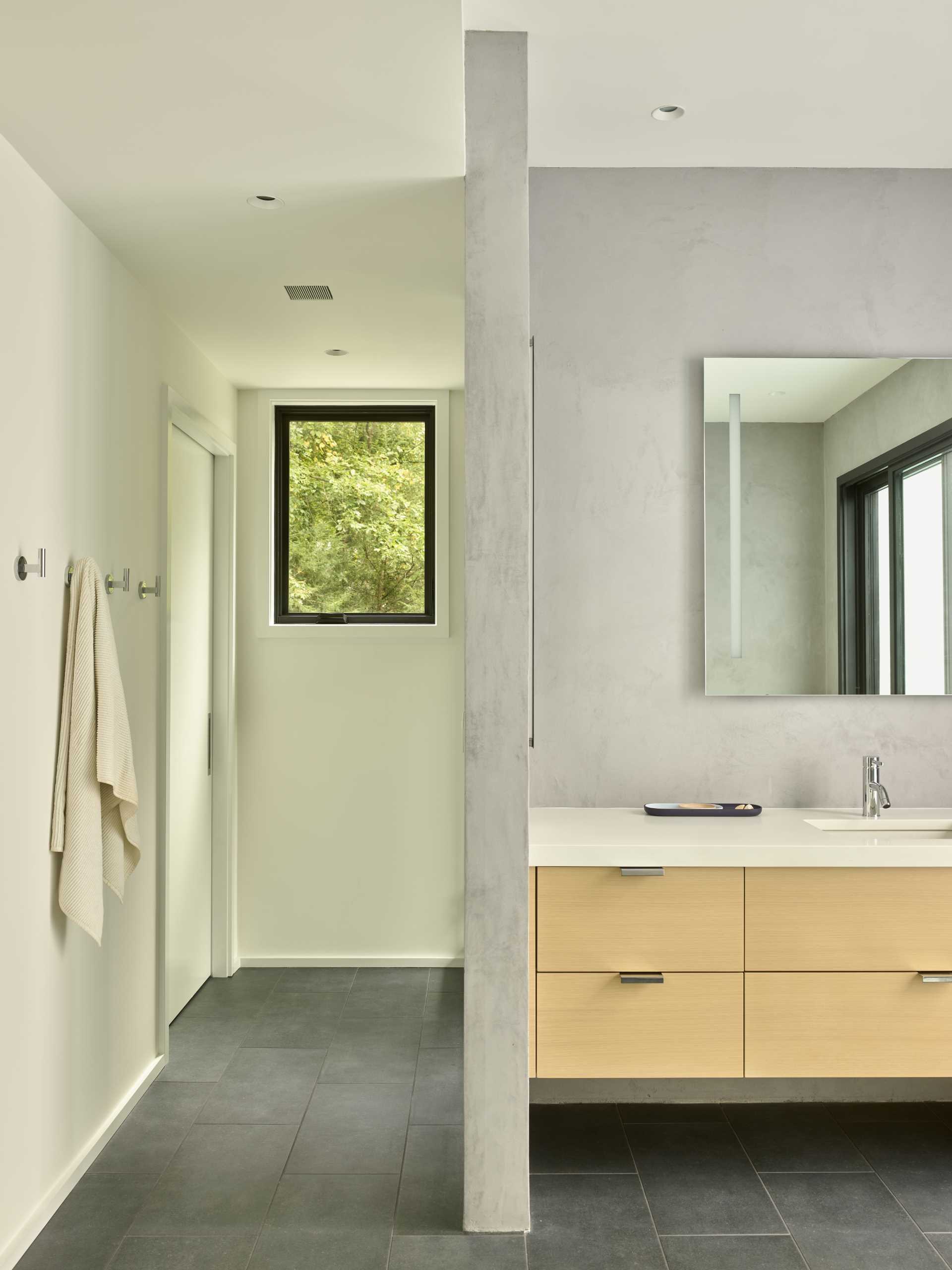 A modern bathroom with a window that frames the forest view.