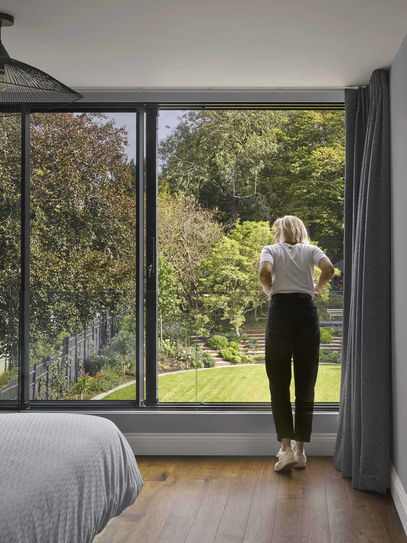 In this modern bedroom, a large sliding window can be opened, with a glass railing for safety.