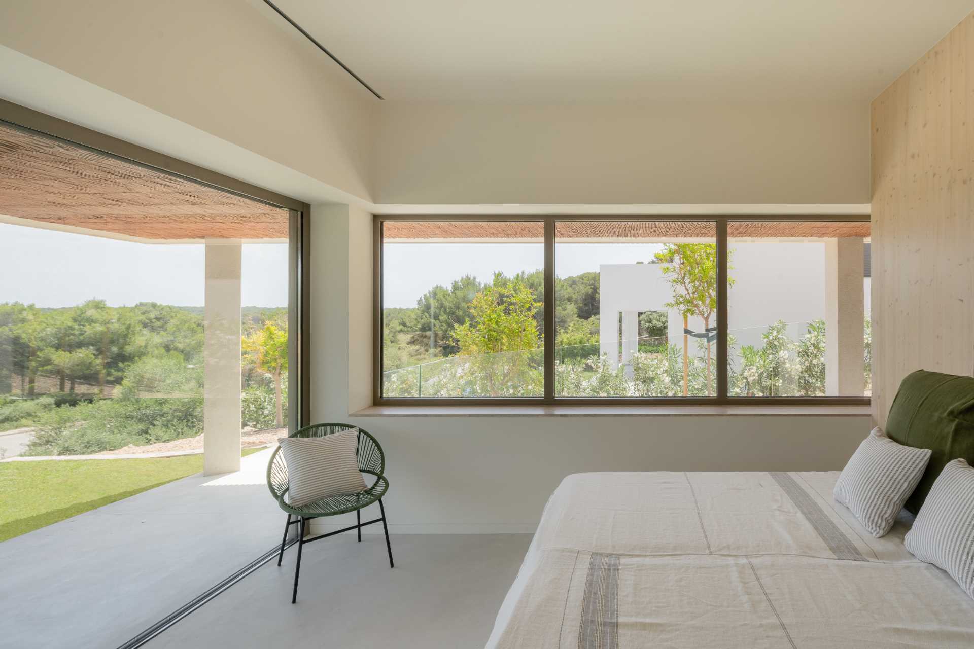 A modern bedroom with a sliding door that opens to a shaded terrace.