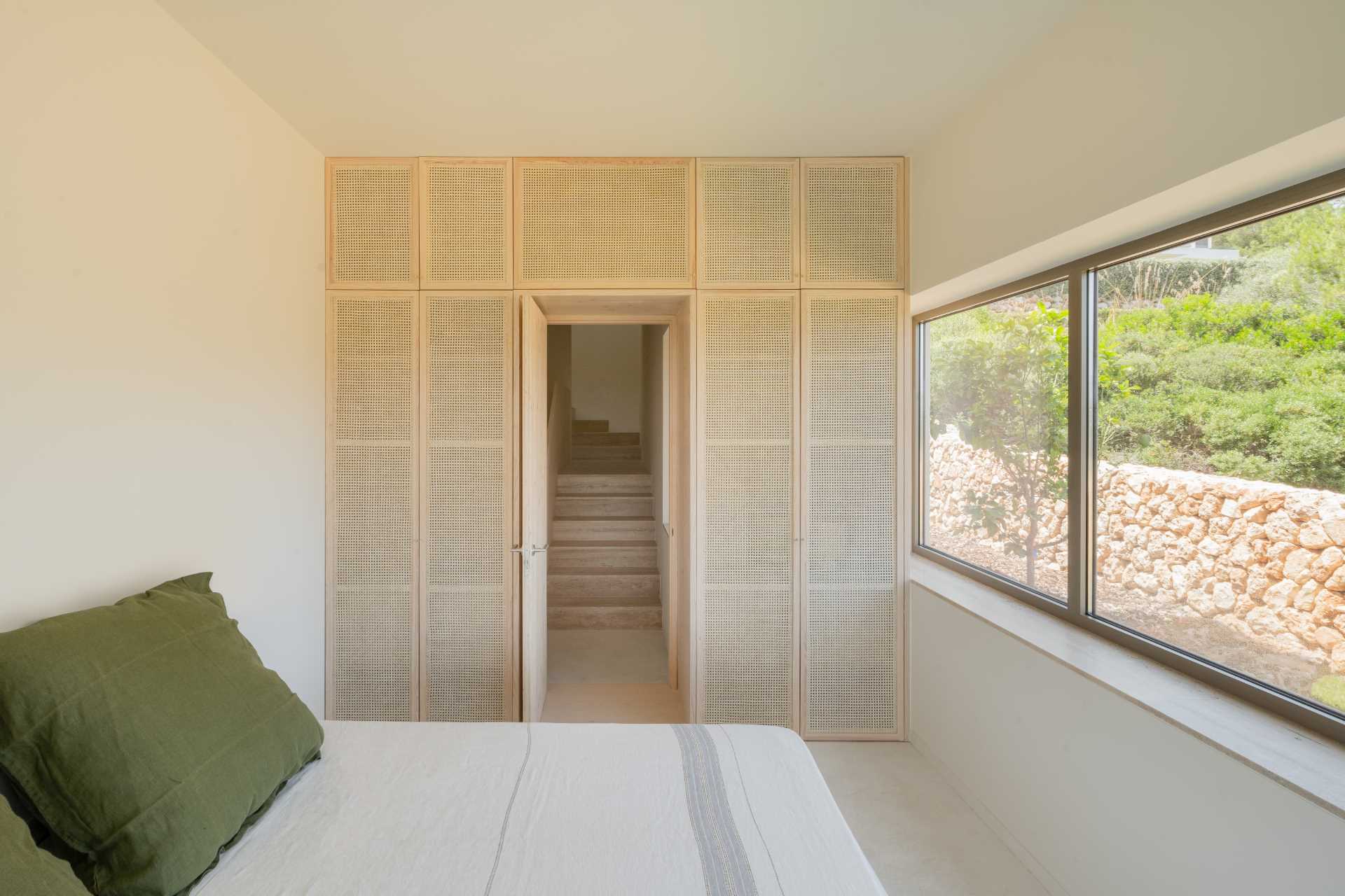 A modern bedroom with artisanal rattan and light pine wood carpentry.