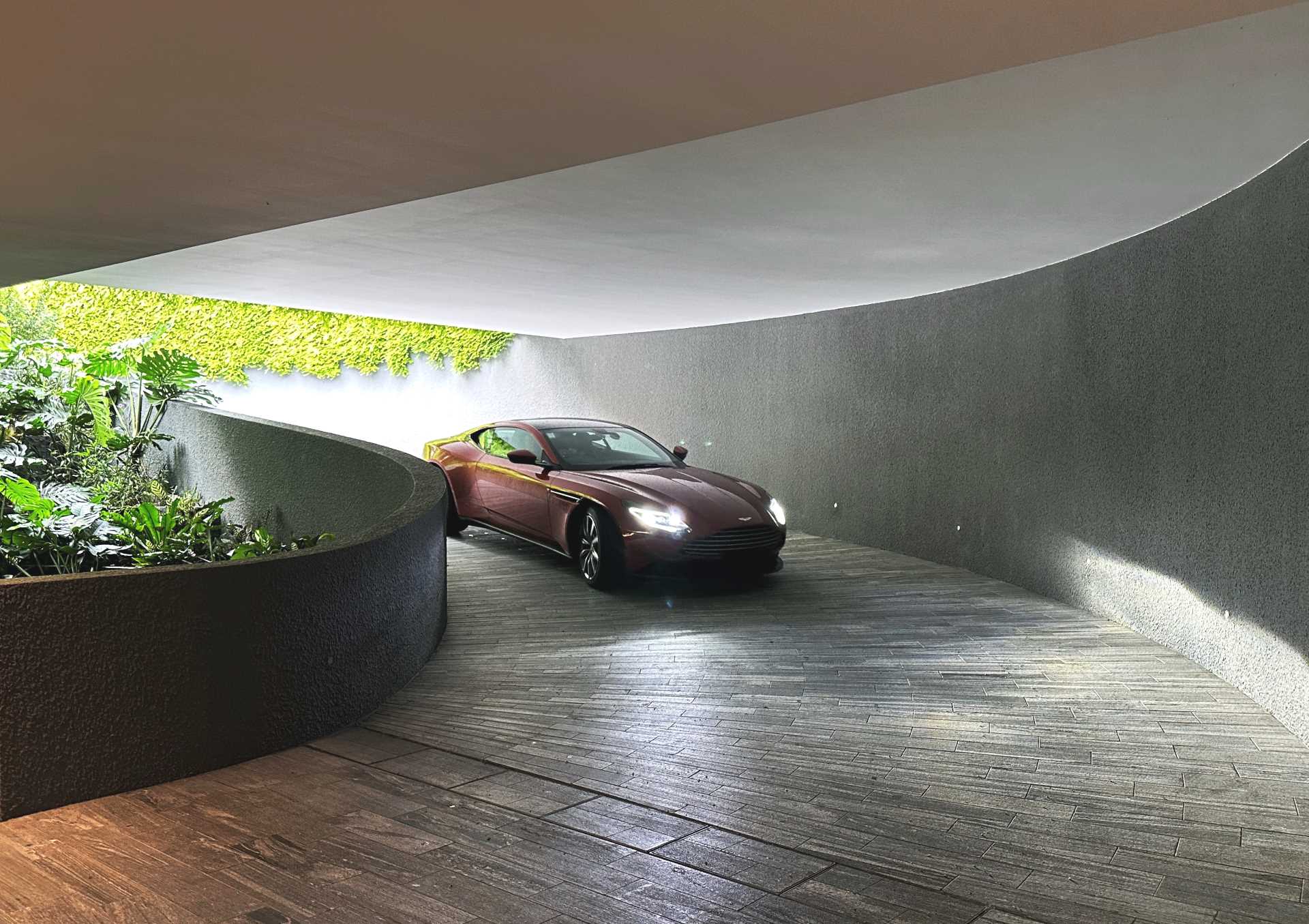 A modern home with a curved driveway that leads underground.