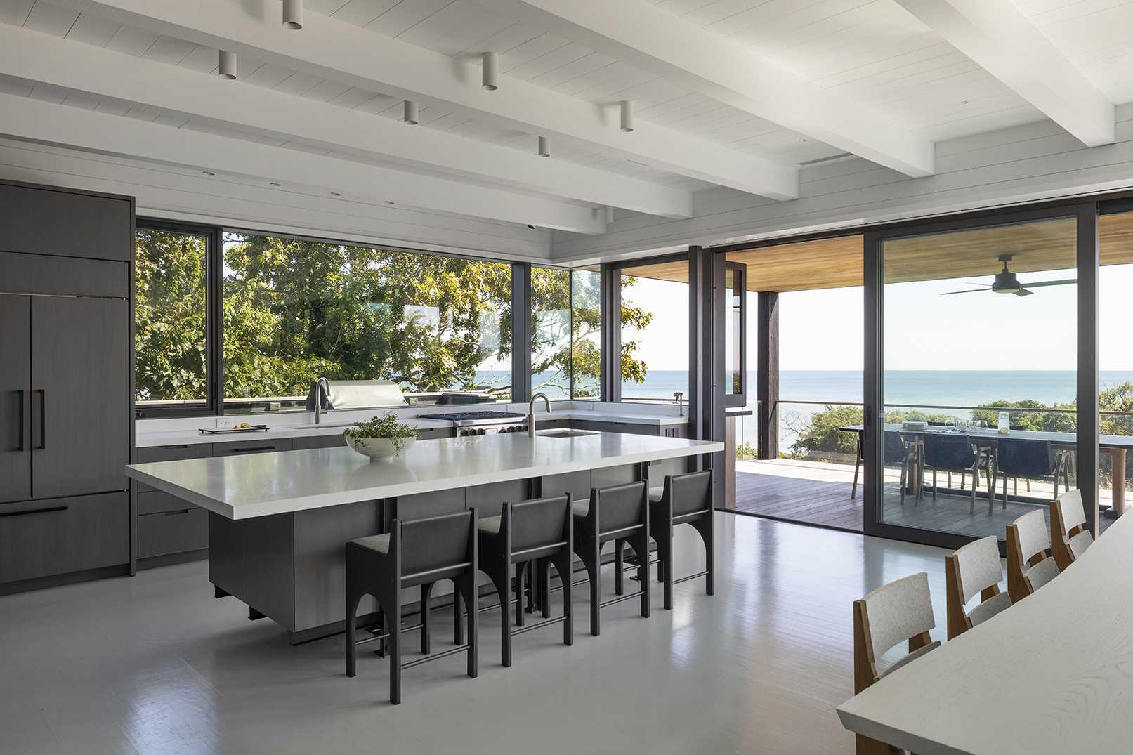 A modern kitchen with a large island opens to a covered deck with outdoor dining.