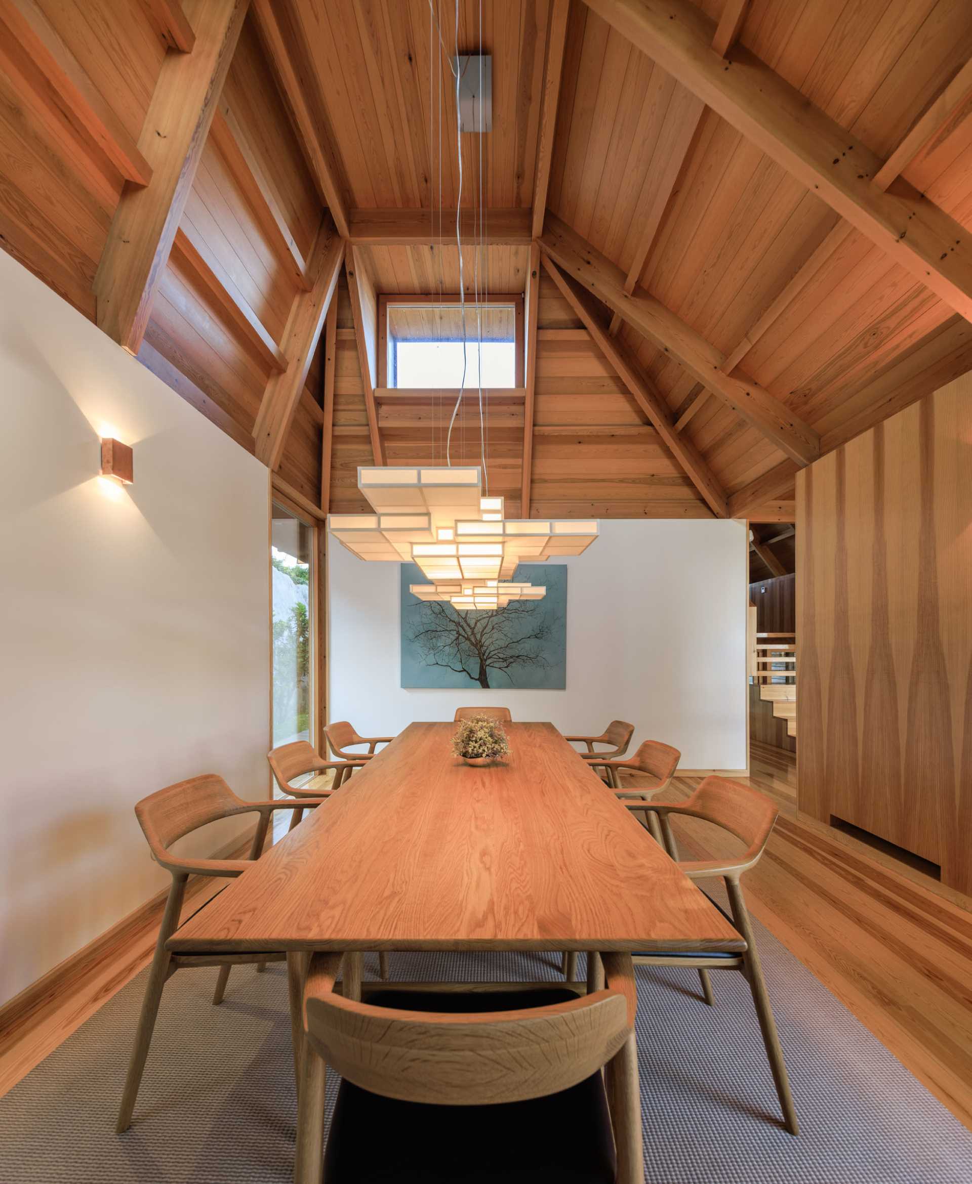 A modern dining room with an angular wood ceiling.