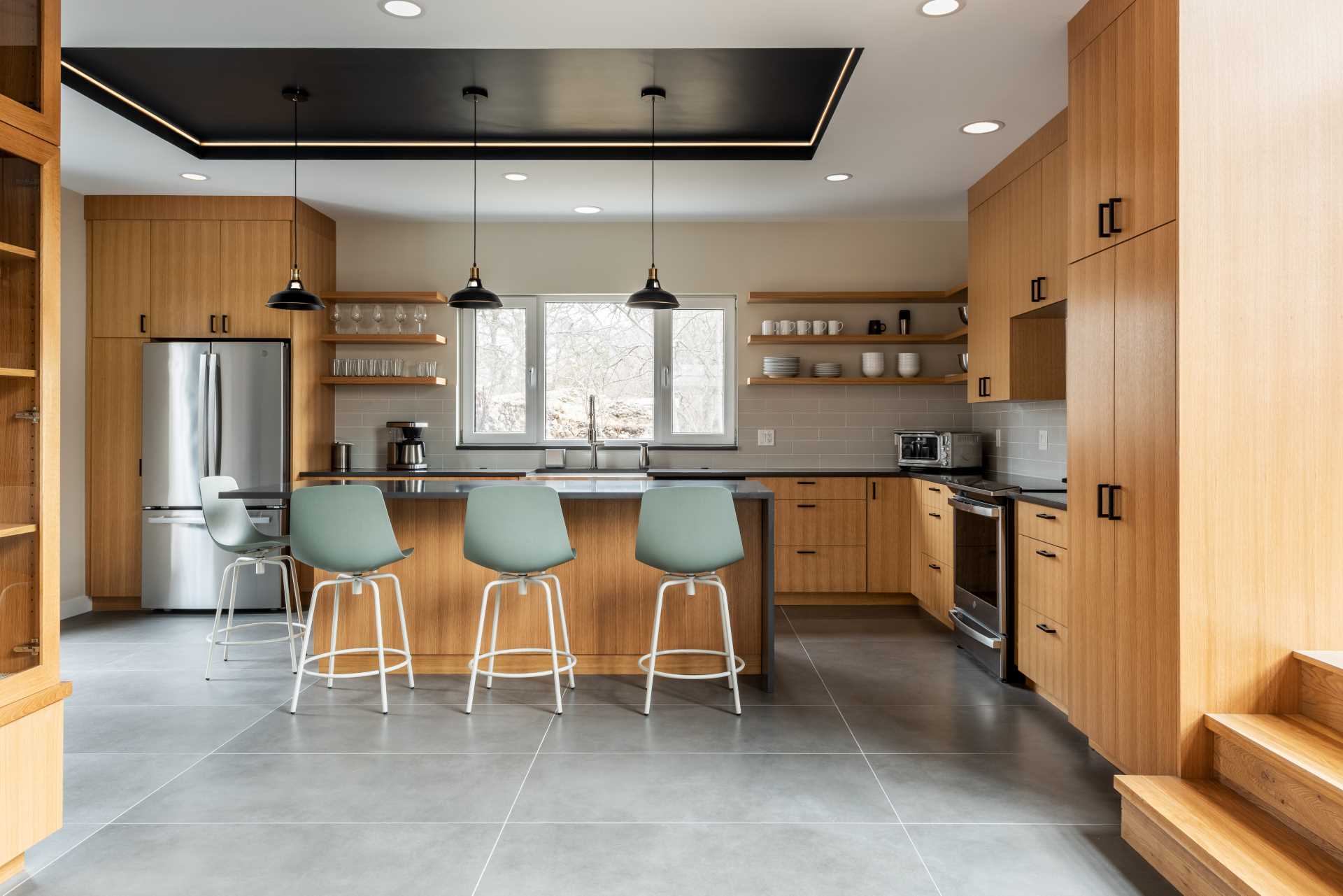 A modern wood kitchen with dark countertops, an island, and concrete flooring.