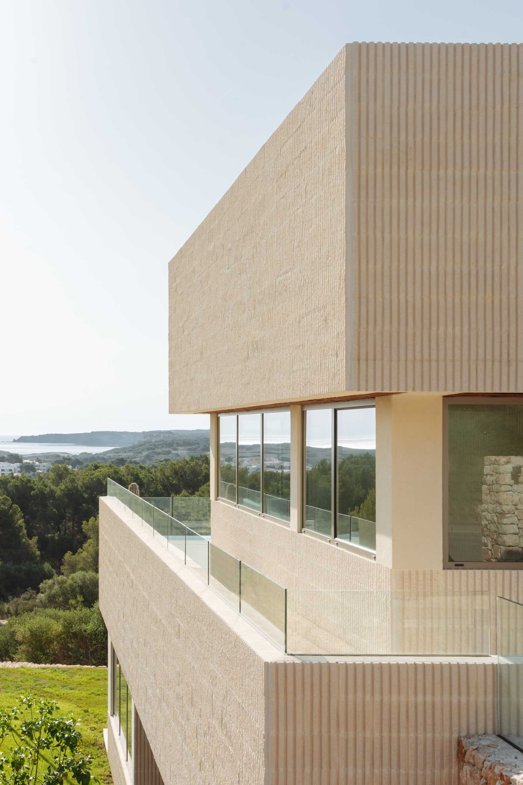 A modern multi-storey home in Menorca, Spain, that features a textured facade of fluted concrete walls.