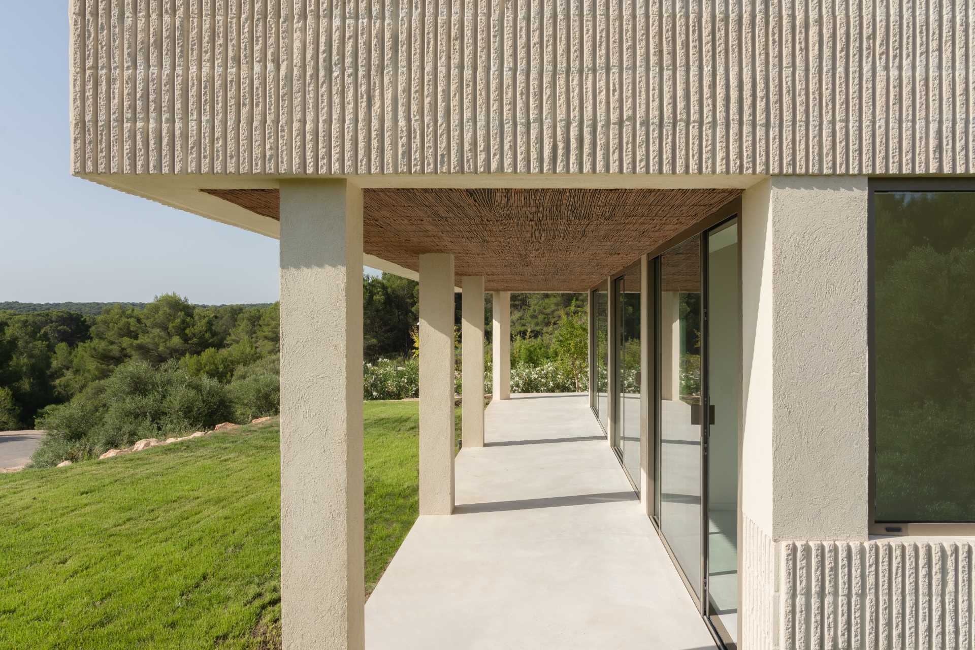 A modern multi-storey home in Menorca, Spain, that features a textured facade of fluted concrete walls.