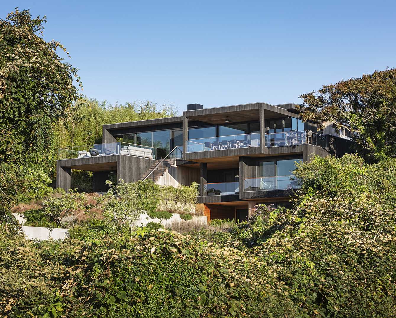 A modern multi-level home with a pool house that includes a green roof.