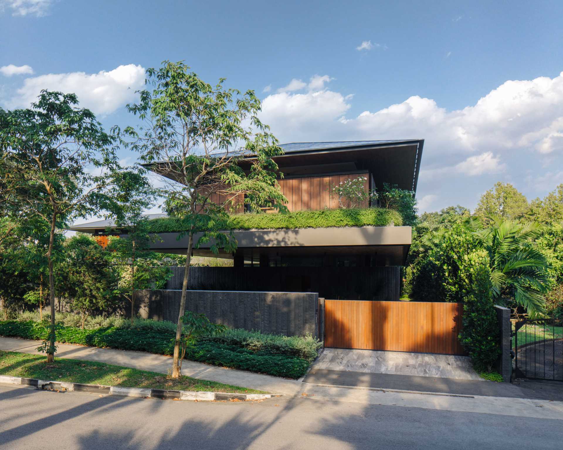 A long stone wall lined with vertical plantings and tall trees conceals a large part of this modern house, offering privacy and a welcome disconnect from the city surroundings.