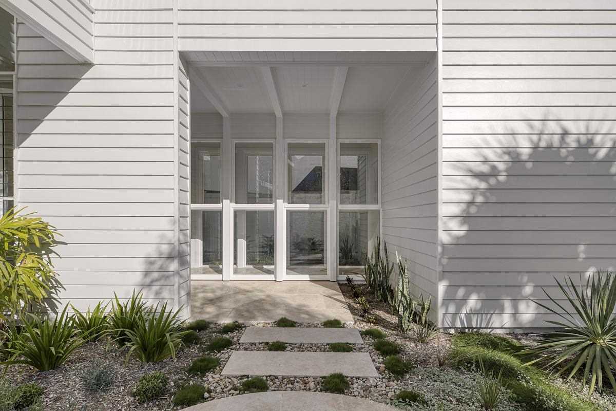 Inspired by coastal living, this modern home features an exterior of white weatherboards and white battens.