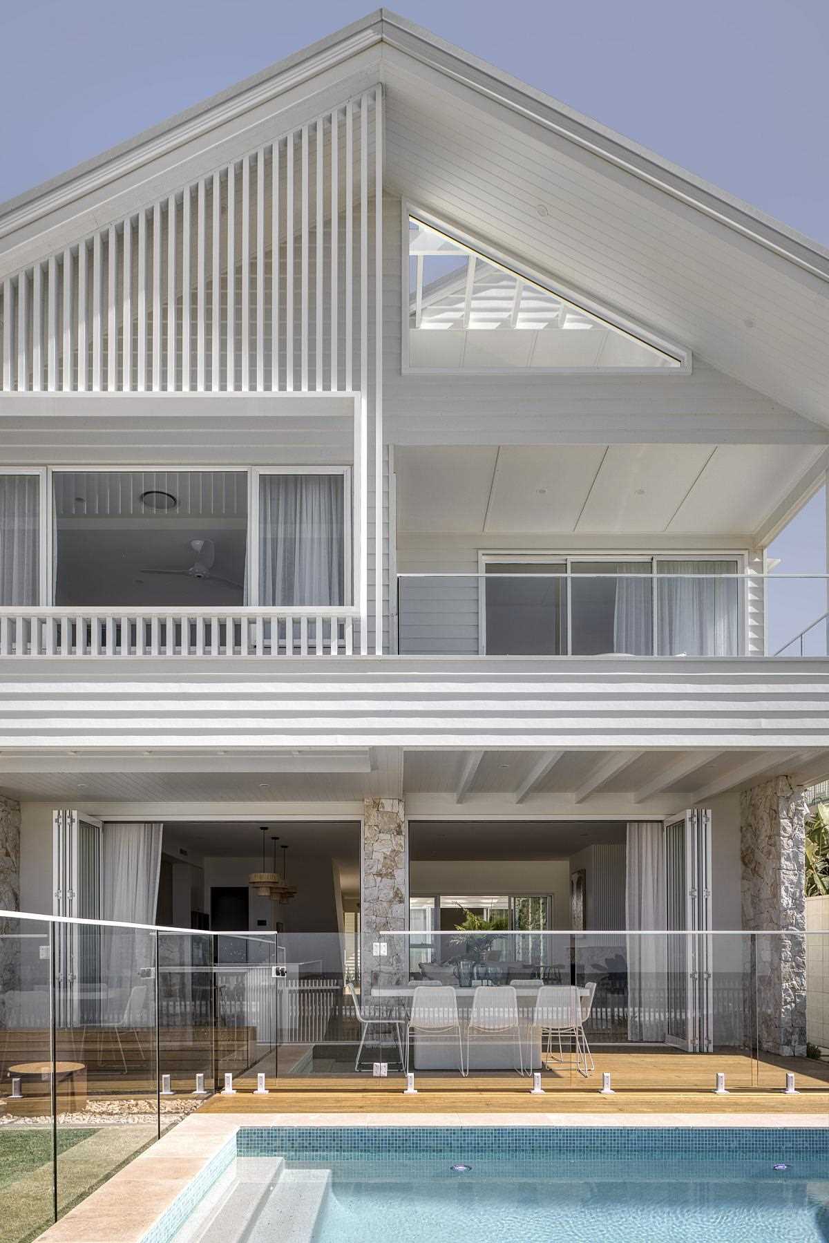 A modern coastal home with a designated outdoor space area for sitting, dining, and a swimming pool.