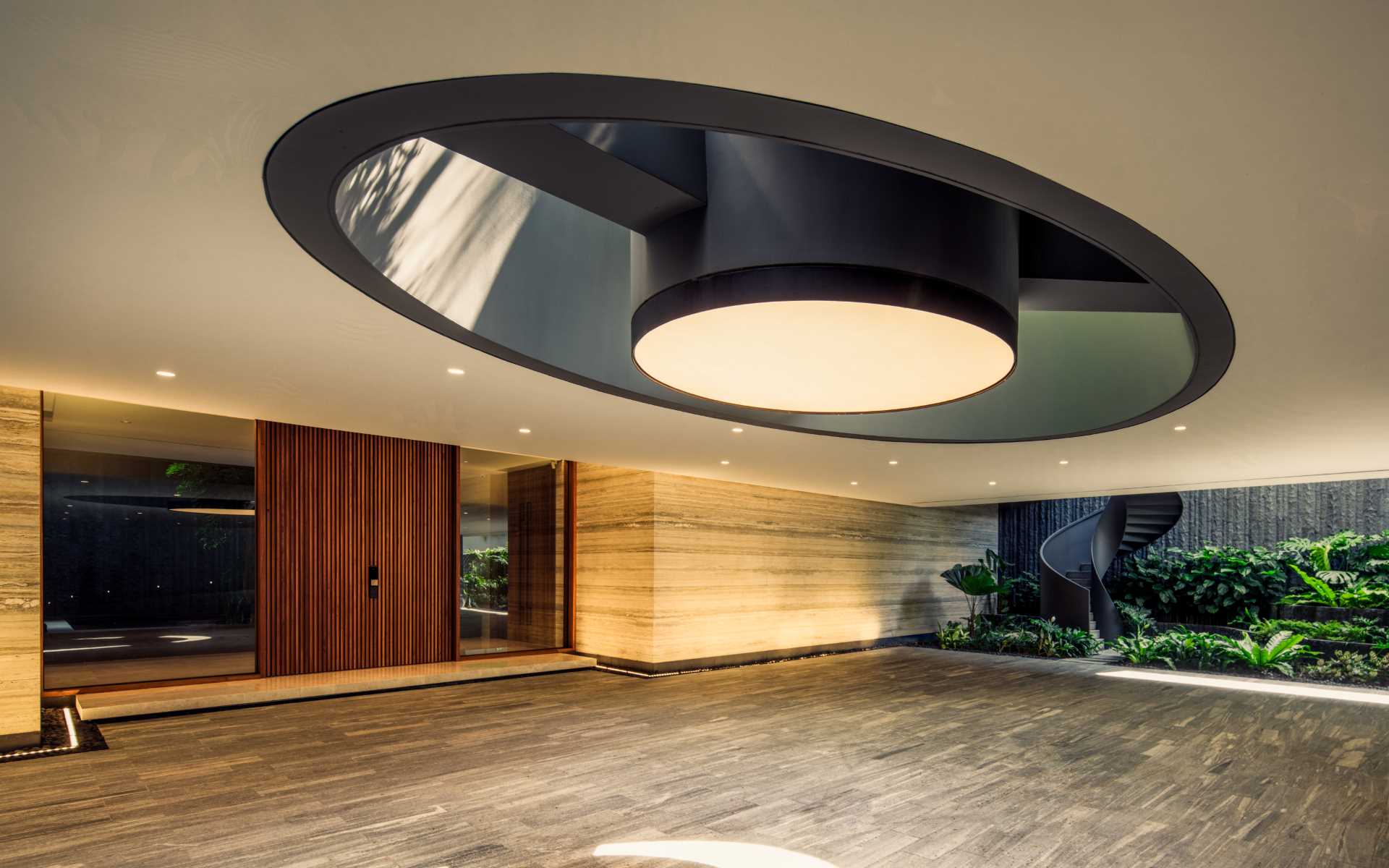 A modern home with a large wood front door, and a skylight in the underground driveway.