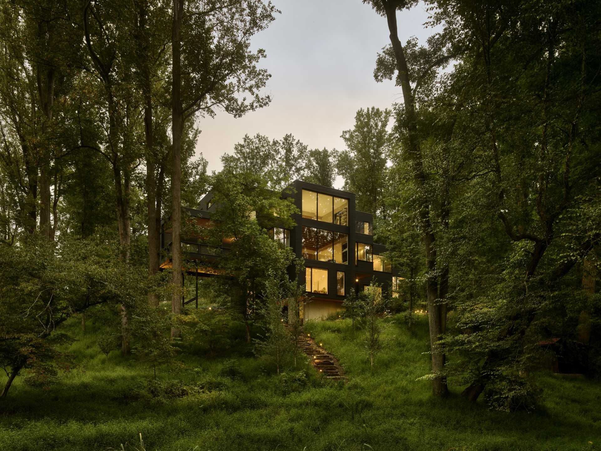 A modern home with an abundance of windows, is also surrounded by forest.