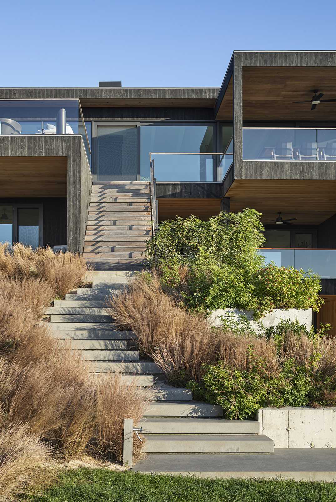 Exterior stairs of this modern home connect the various levels of the home with the garden below and the swimming pool.