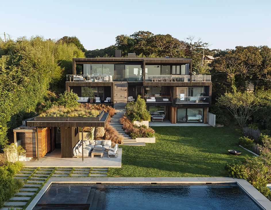 A modern multi-level home with a pool house that includes a green roof.