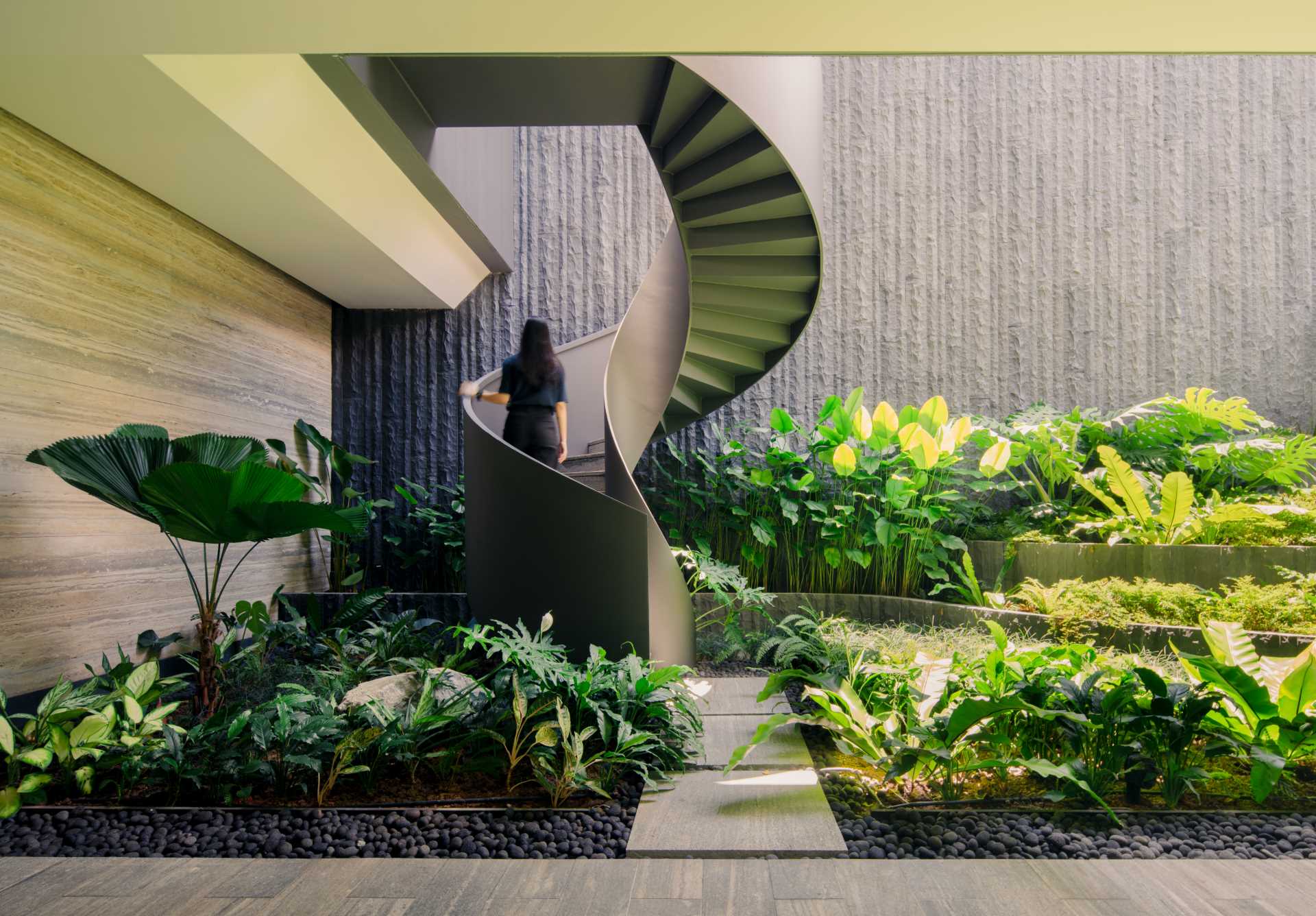 A modern home with external spiral stairs that's surrounded by plants.