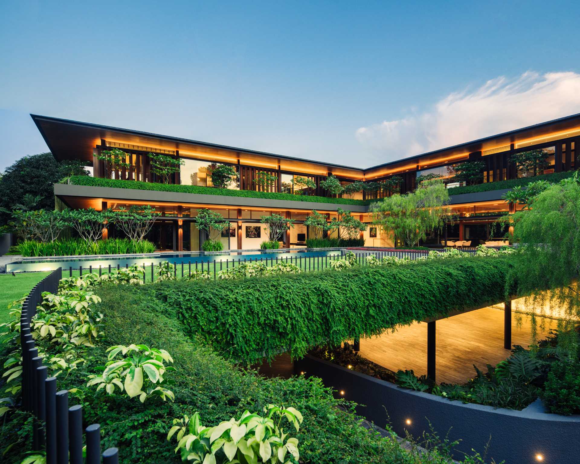 A modern house surrounded by plants, that also includes a swimming pool and underground carpark.